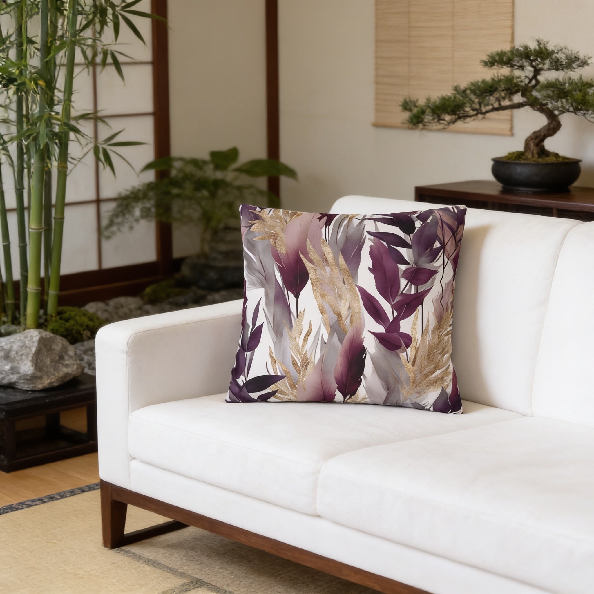 a living room with a white sofa, a decorative pillow with a leaf pattern, and a potted plant.