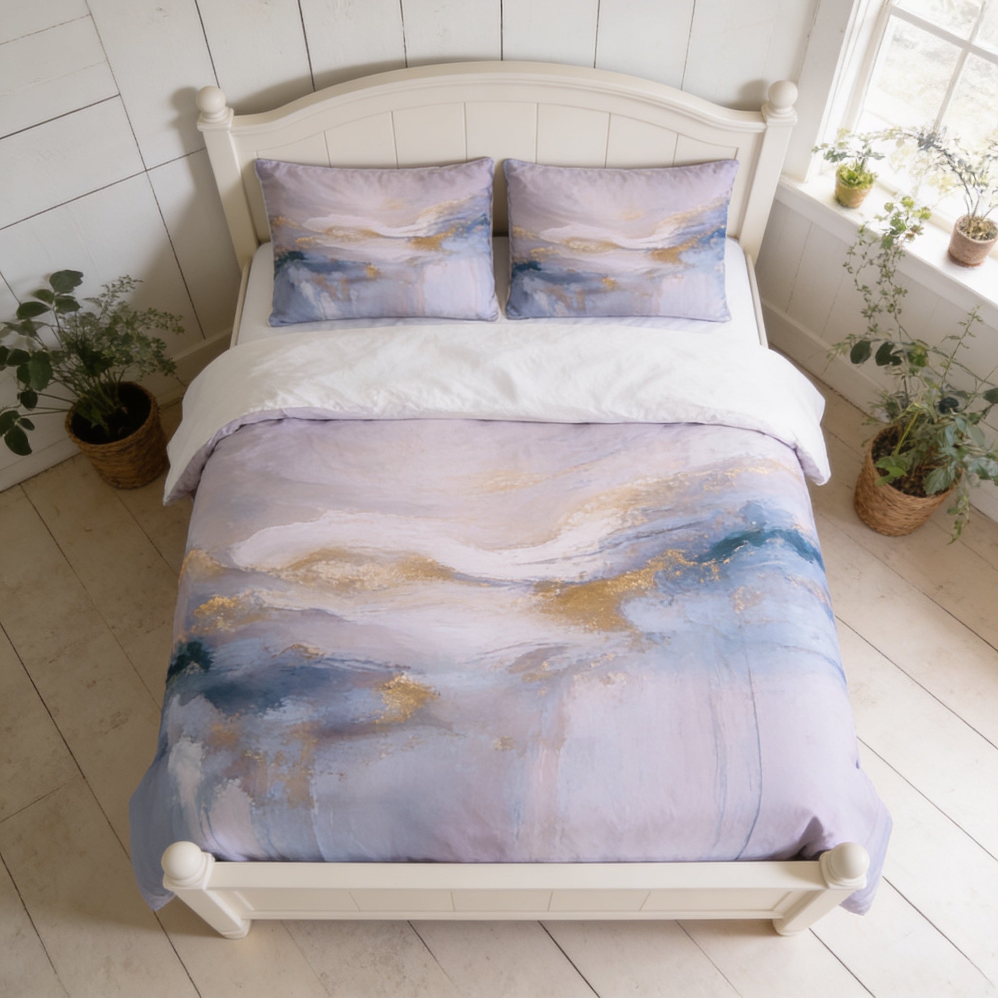 a bedroom with a white wooden bed frame, a white comforter with a colorful abstract design, and two potted plants on either side of the bed.