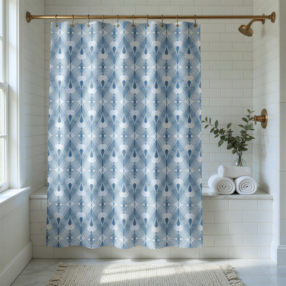 a bathroom with a shower curtain featuring a blue and white geometric pattern. The shower curtain is hanging from a gold rod, and there is a white towel and a small plant on the counter next to the shower.