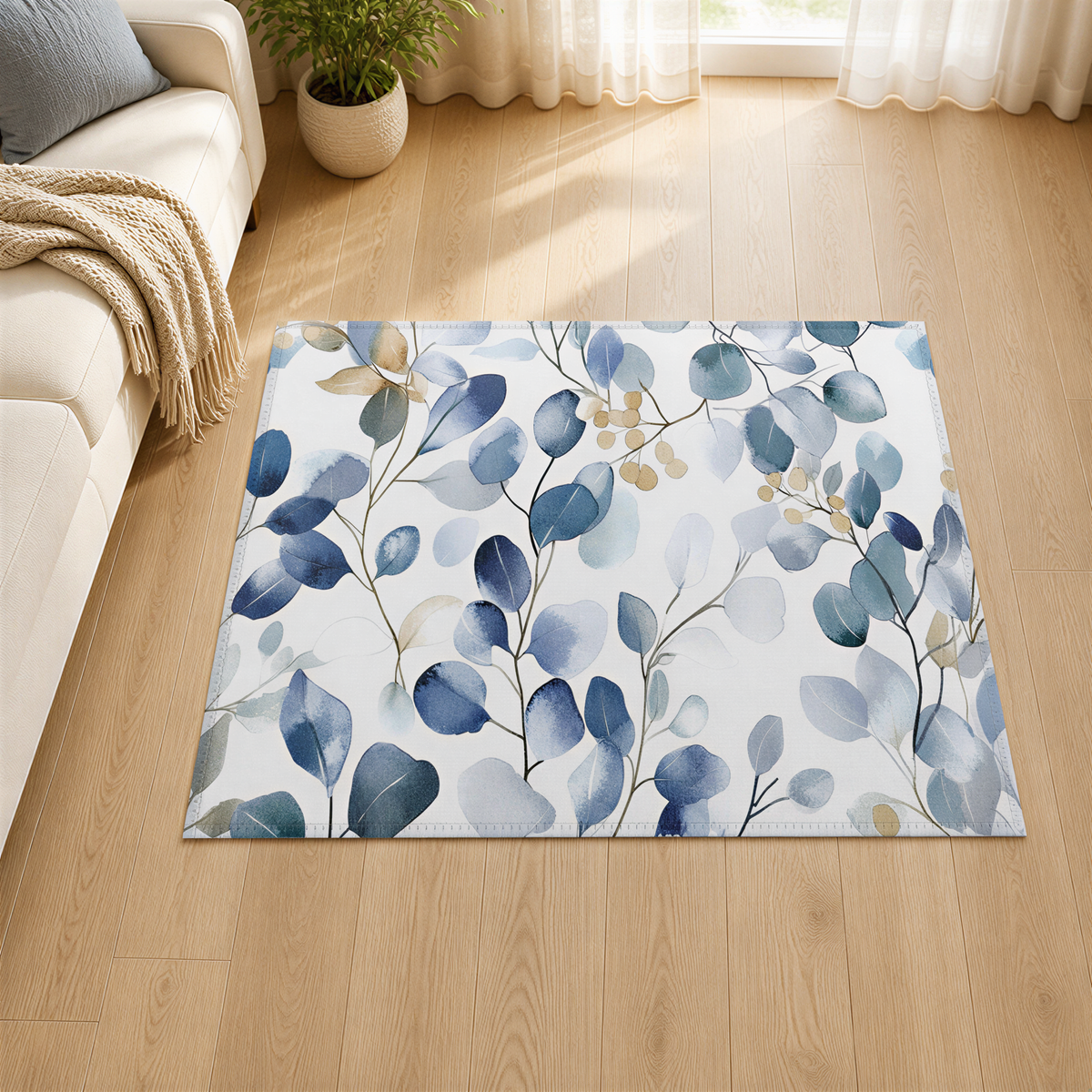 a living room with a large rug on the floor, which has a blue and white leaf pattern. The rug is placed on a wooden floor, and there is a white couch in the background. A potted plant is also visible in the room.
