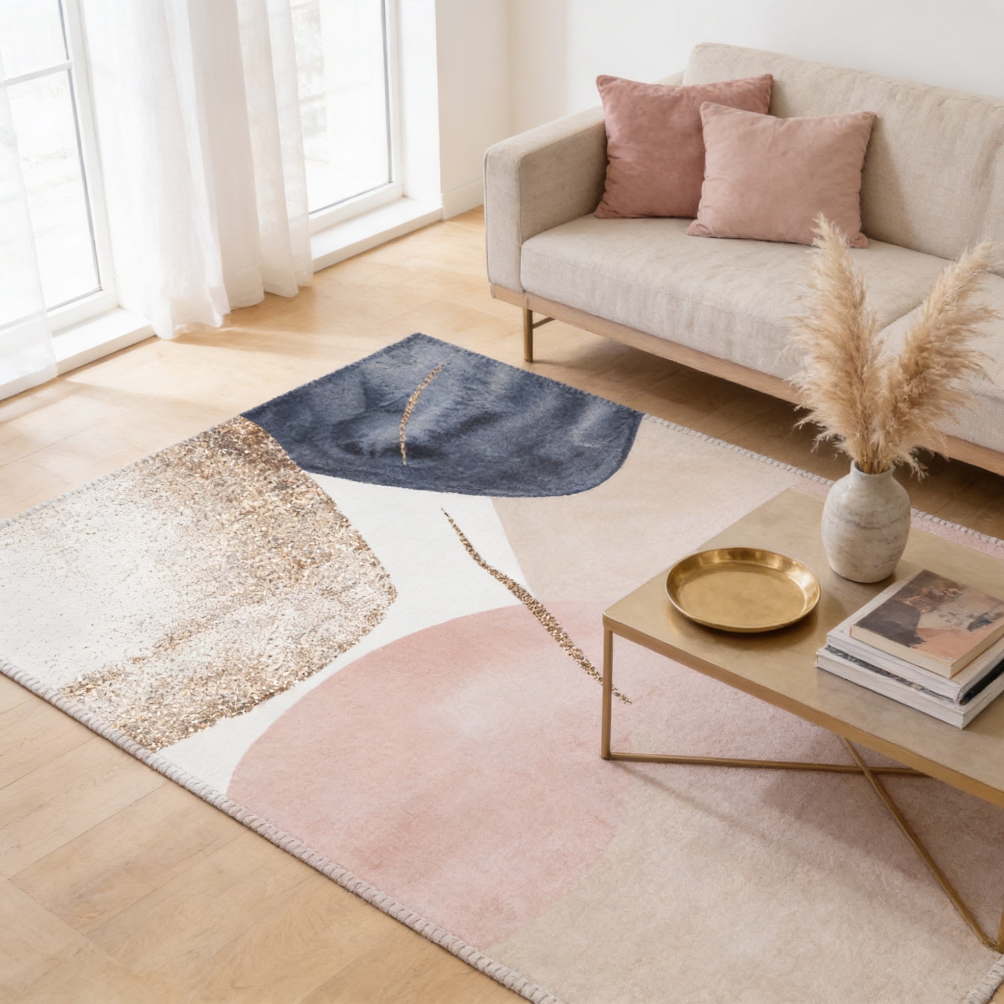 a living room with a beige sofa, a gold-colored coffee table, and a rug with a geometric design in shades of pink, blue, and white.