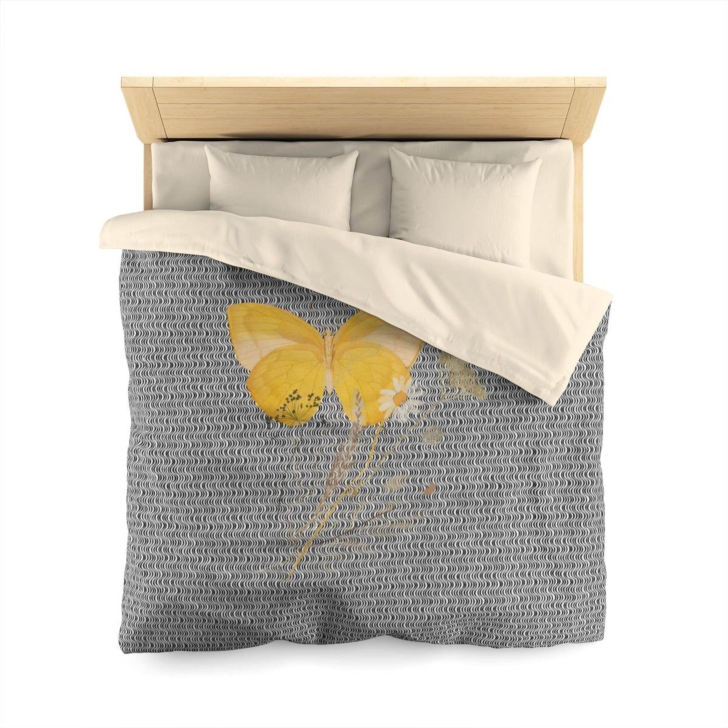 a bed with a gray and white patterned comforter featuring a yellow butterfly design.