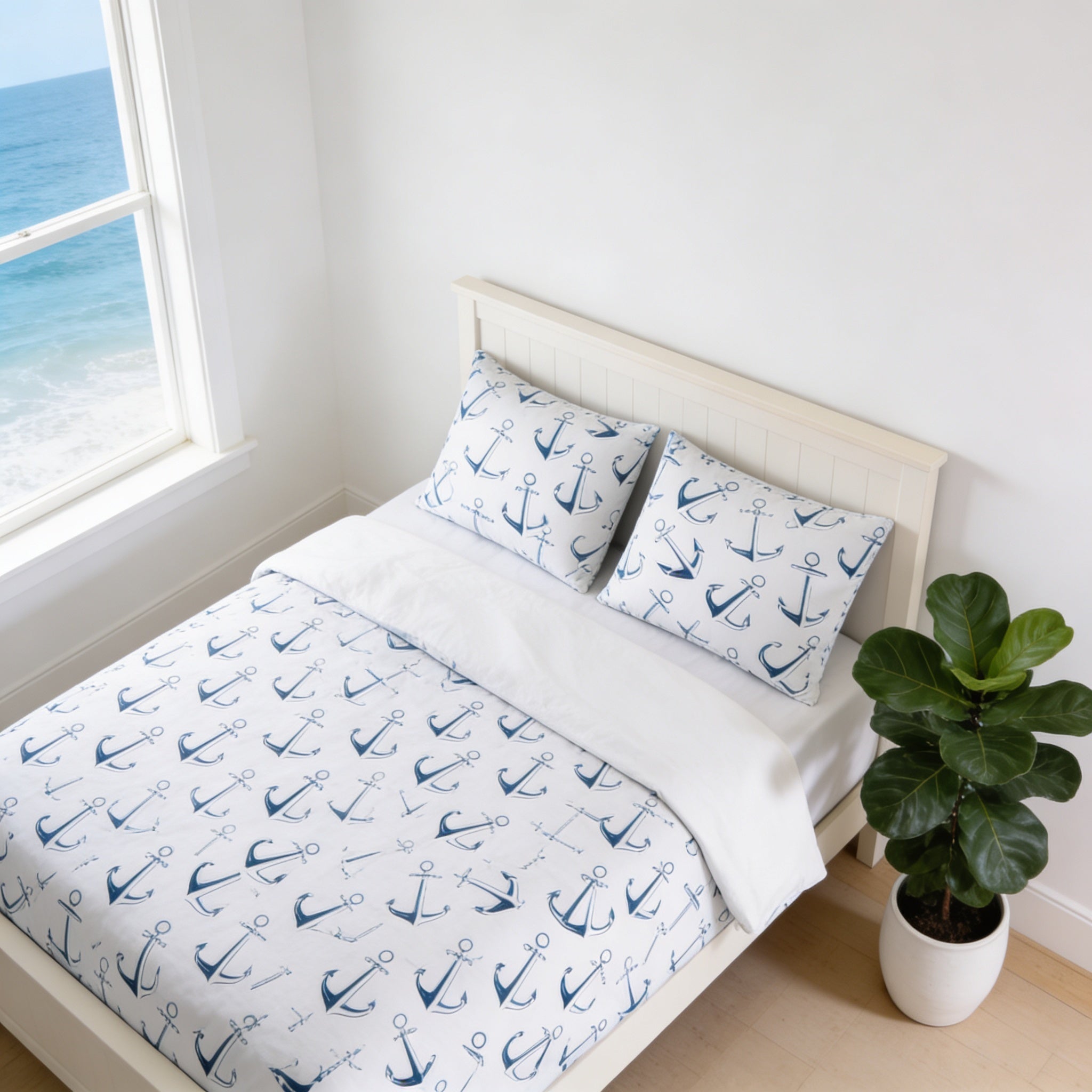 a bedroom with a bed featuring a white headboard and a white comforter with a navy blue anchor pattern. The bed is positioned next to a window overlooking the ocean, and there is a potted plant on the floor next to the bed.