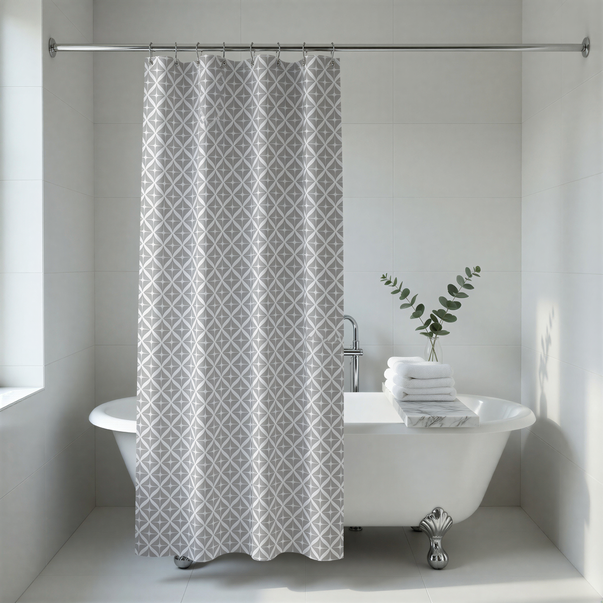 A modern bathroom with a white clawfoot bathtub, a gray patterned shower curtain, and a stack of white towels.
