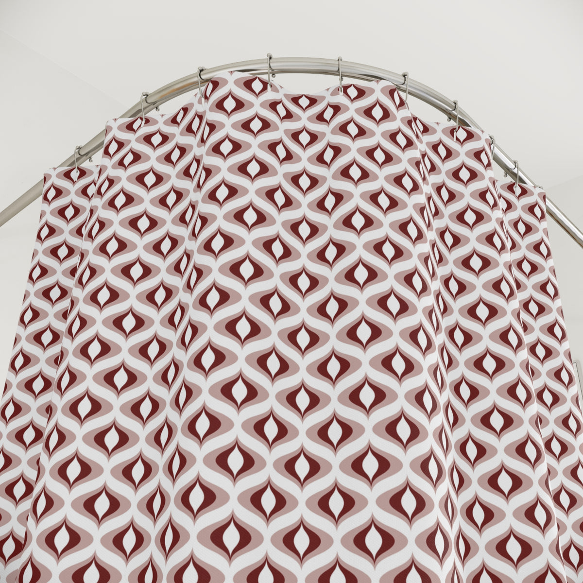a shower curtain with a repeating pattern of red and white geometric shapes, hanging from a curved rod.