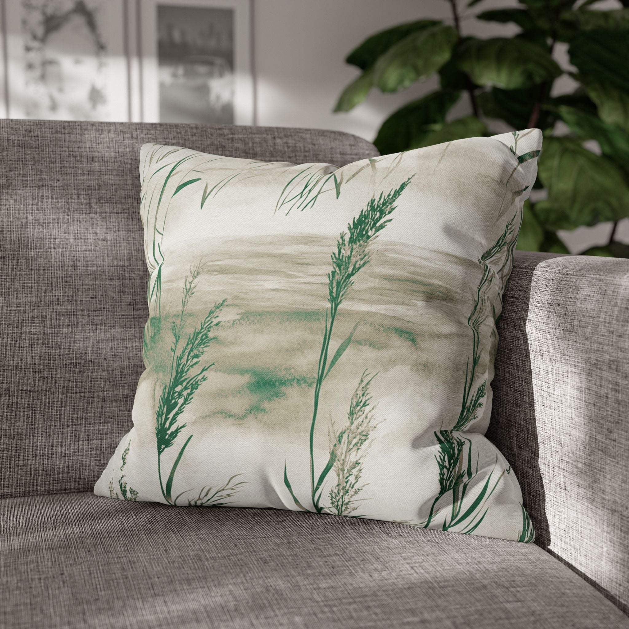A gray sofa with a decorative throw pillow featuring a green plant design.