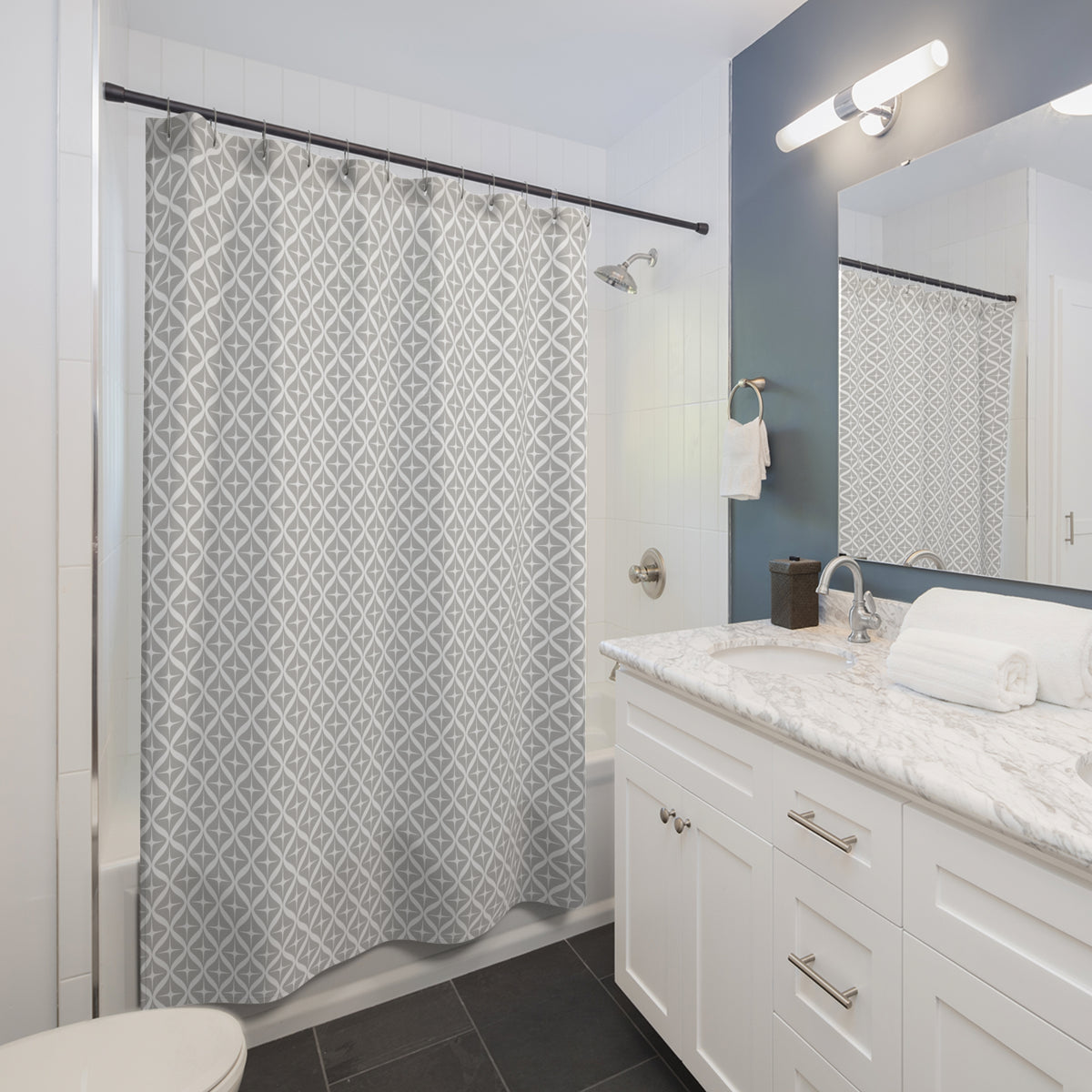a modern bathroom with a white vanity, a gray and white patterned shower curtain, and a mirror above the vanity.