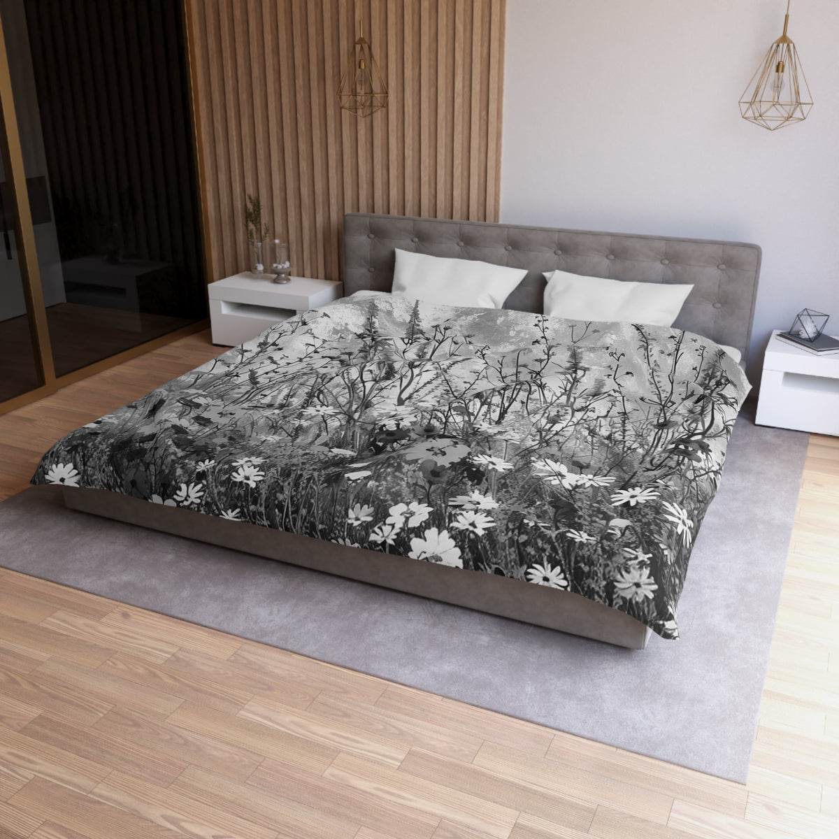 a modern bedroom with a large bed covered in a black and white floral patterned comforter. The bed is positioned against a wall with a wooden paneling, and there are two nightstands on either side of the bed. The room has a minimalist and clean design, with a gray rug on the floor and a wooden floor.