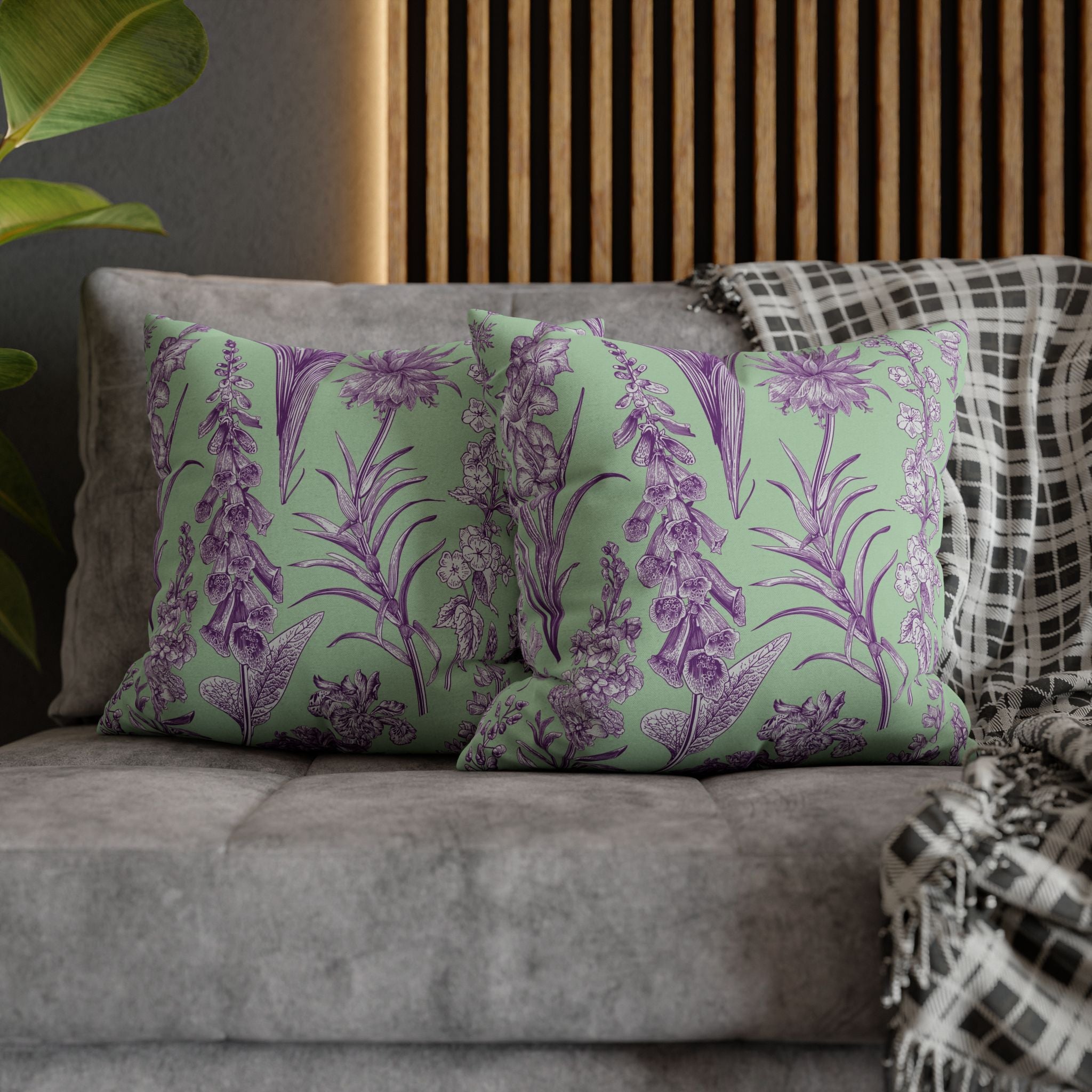 a gray couch with two green throw pillows adorned with a floral pattern in shades of purple and white. The pillows are arranged in a way that they rest on the couch, creating a cozy and inviting atmosphere.