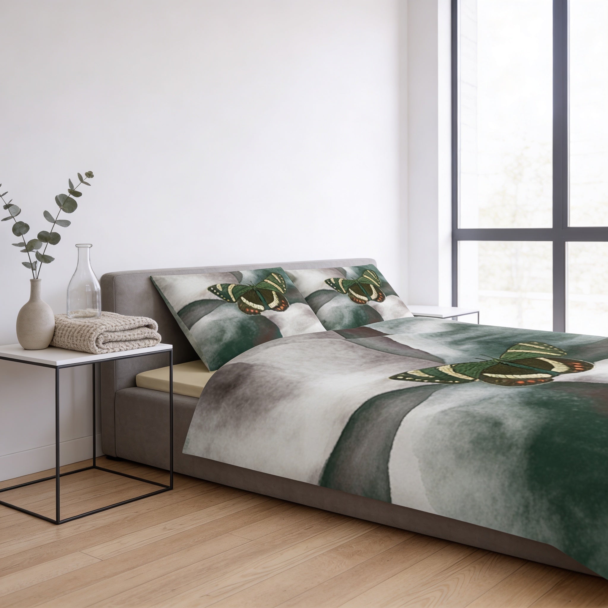 a bedroom with a bed, a nightstand, and a window. The bed has a green and gray patterned comforter and matching pillows. The nightstand has a vase and a bottle on it. The window is located on the right side of the room.