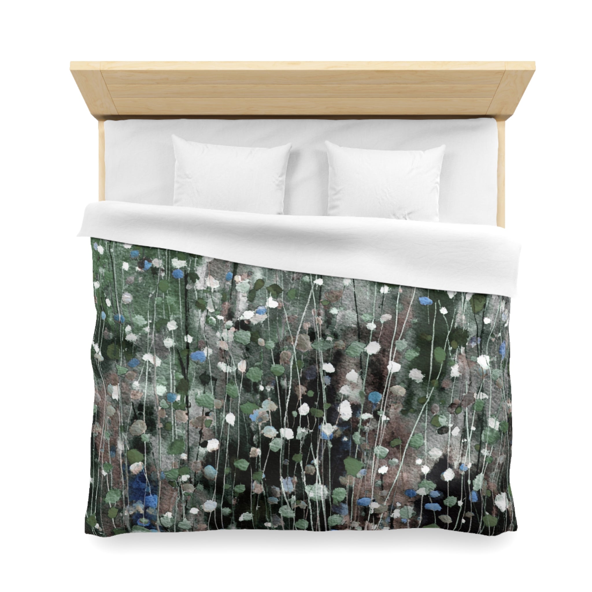 a bed with a green and white floral patterned comforter and pillows.