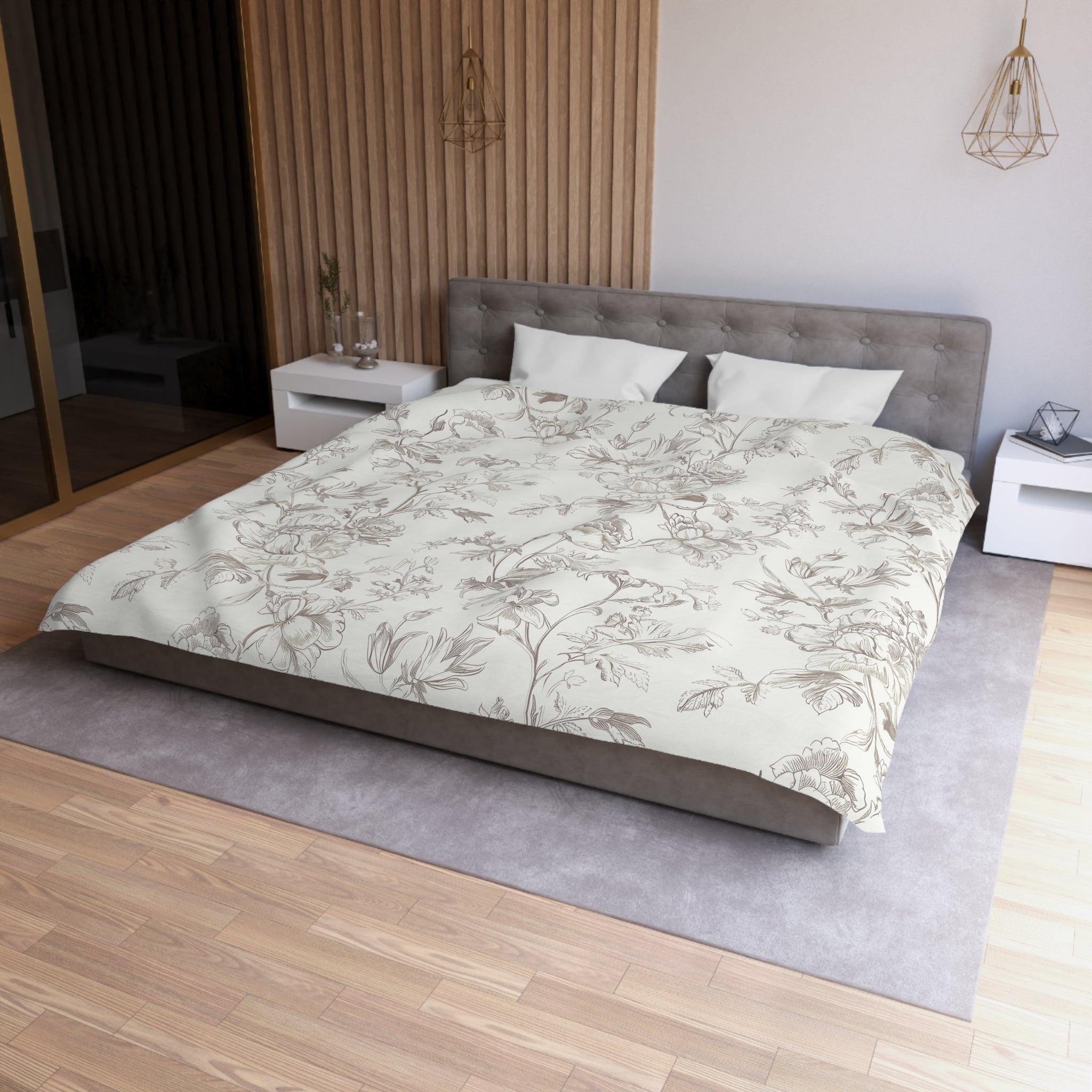 a modern bedroom with a large bed, a gray headboard, and a wooden floor. The bed is covered in a floral print comforter, and there are two white pillows on it. The room also features a nightstand, a pendant light, and a mirror.