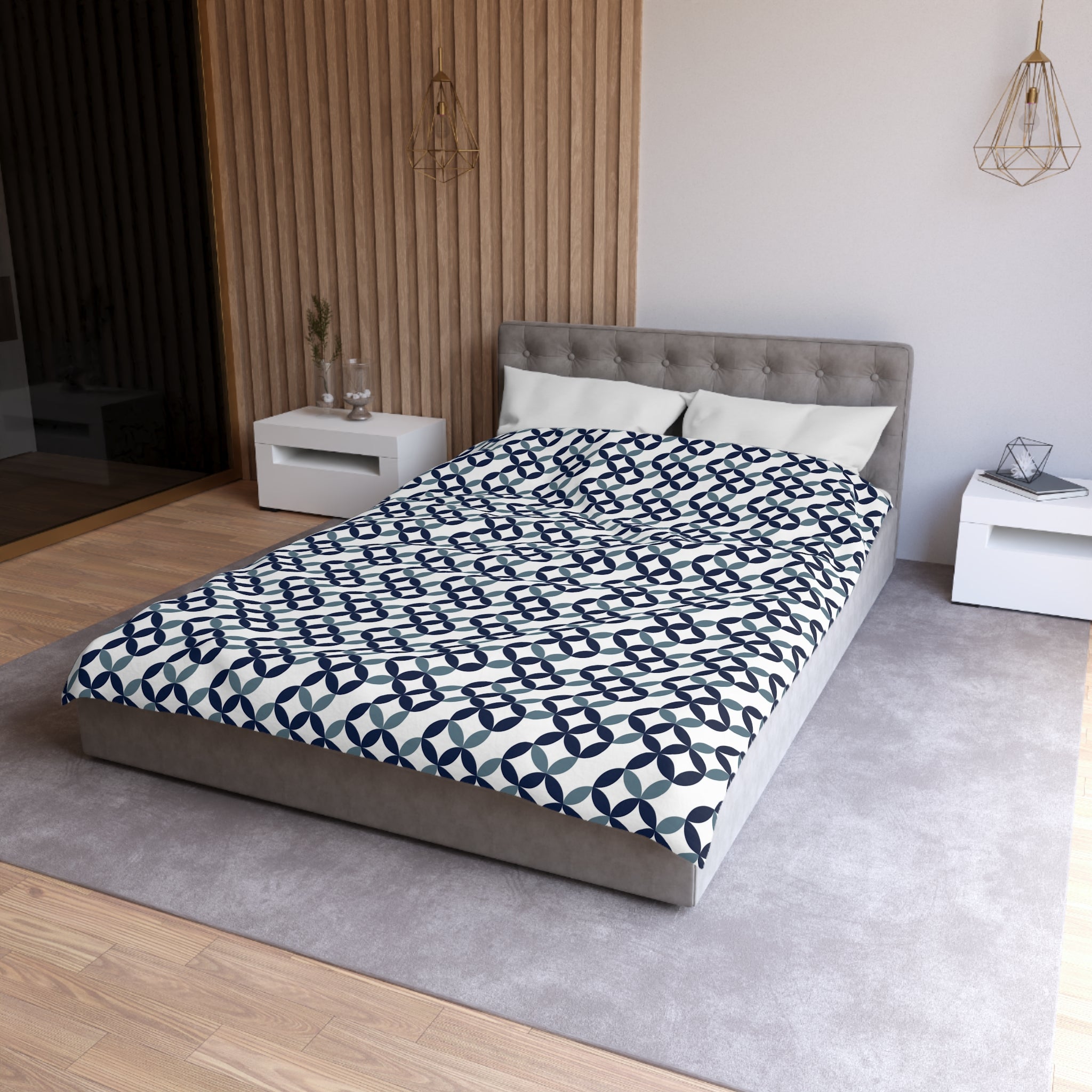 a modern bedroom with a gray tufted headboard, a gray bedspread with a blue and white geometric pattern, and white nightstands on either side of the bed.