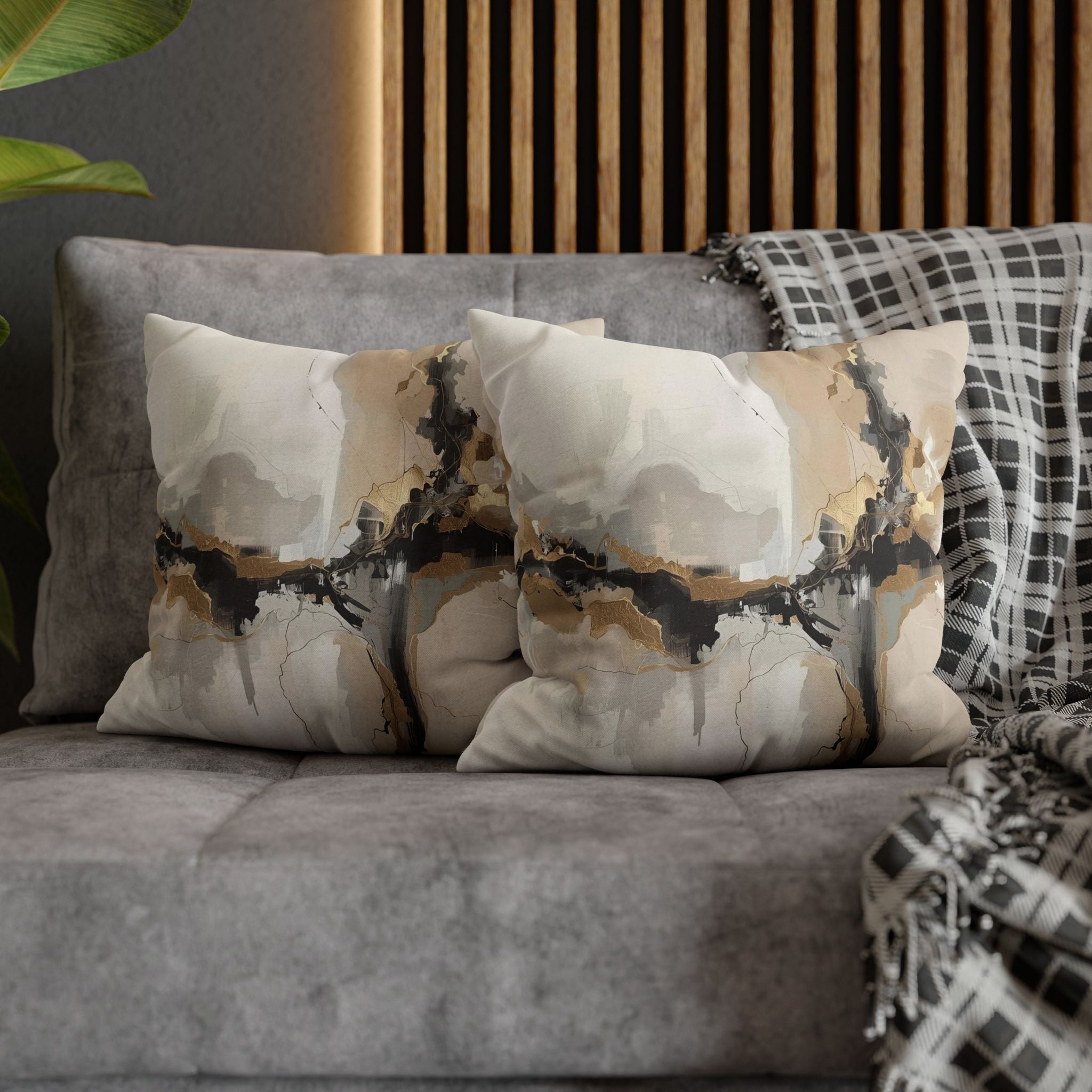 a gray couch with two decorative throw pillows on it. The pillows have a unique abstract design featuring a mix of black, white, and gold colors.