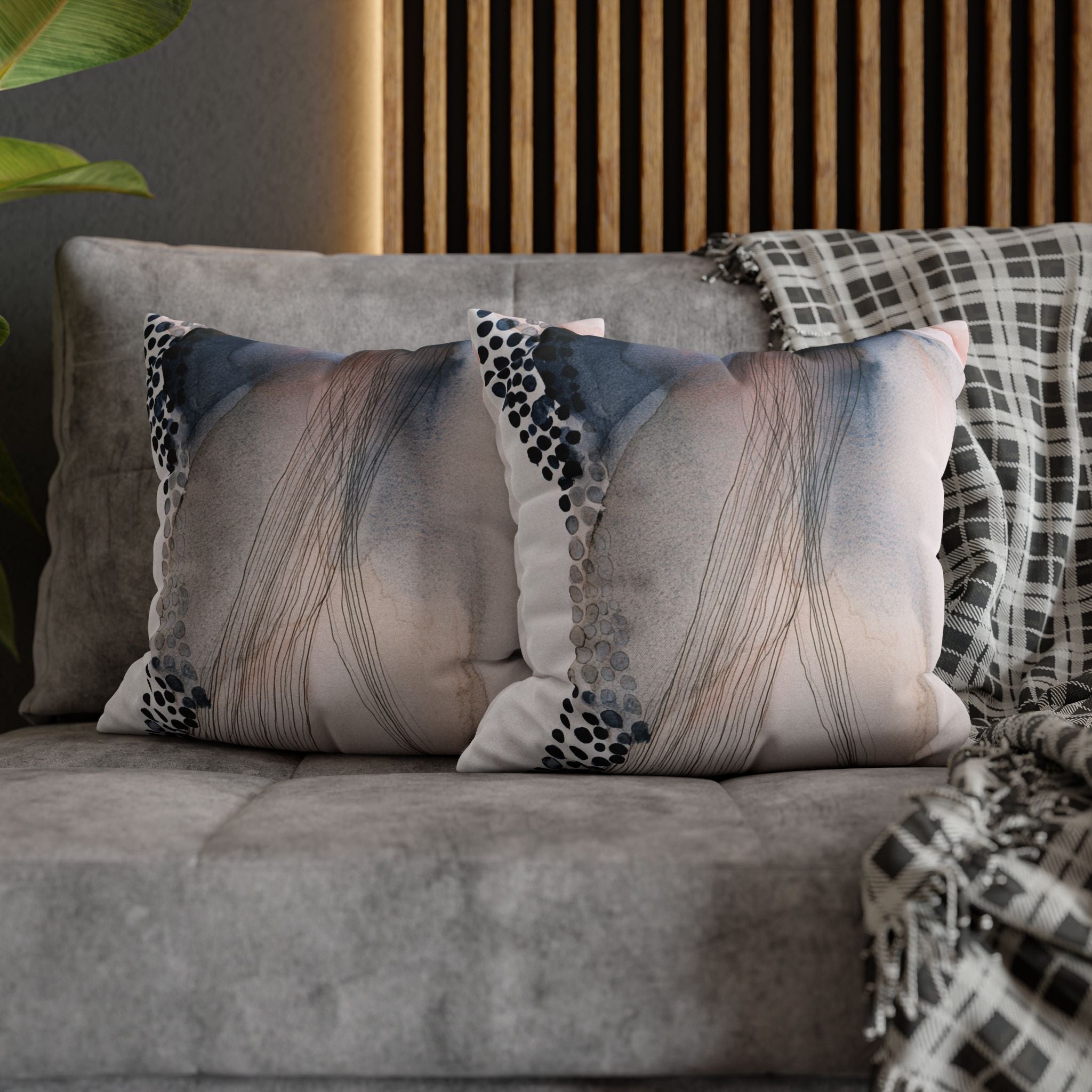 a gray couch with two decorative throw pillows on it. The pillows have a unique abstract pattern with lines and dots in various shades of blue, gray, and white. The pillows are placed on the couch, creating a cozy and stylish seating area.