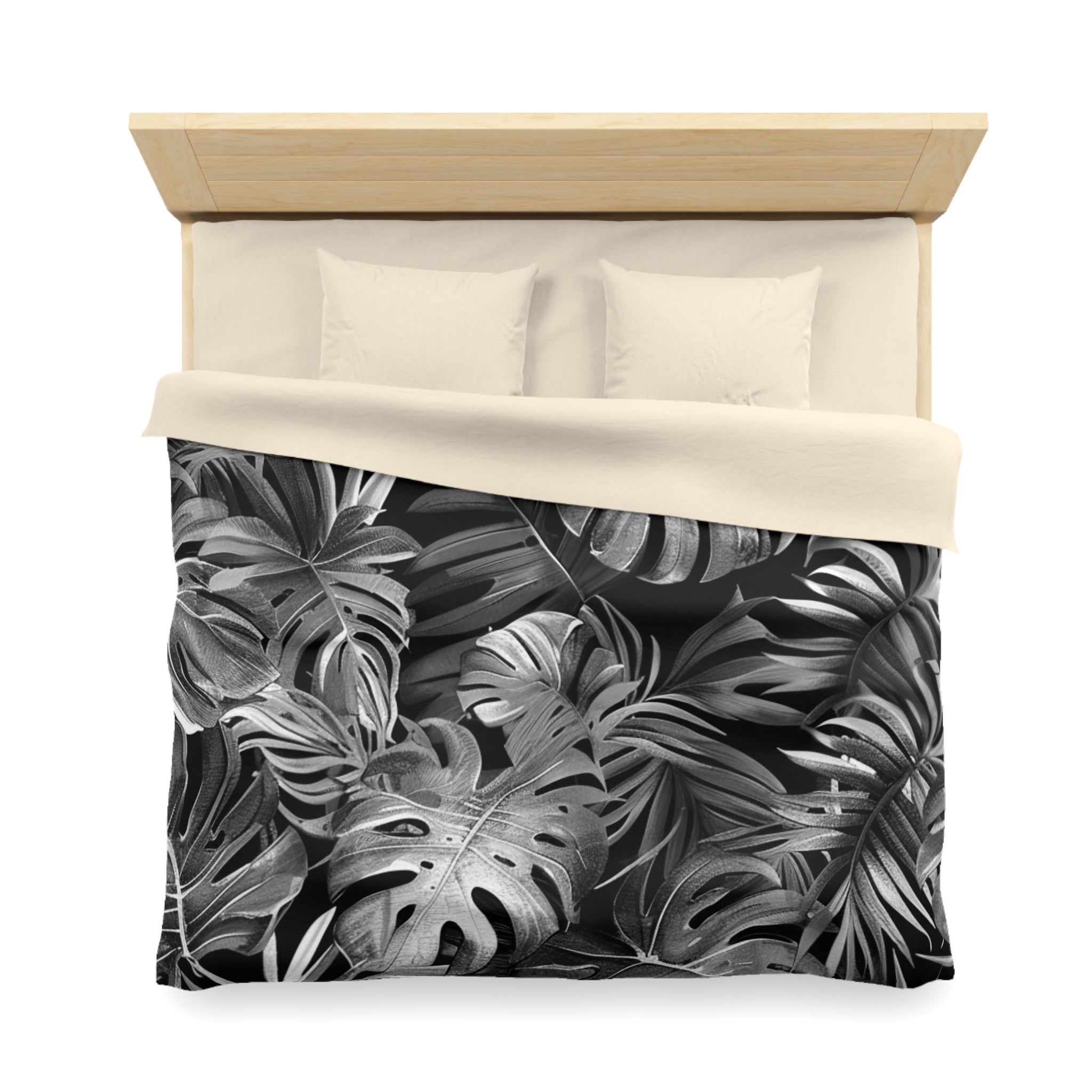a bed with a black and white tropical leaf pattern on the comforter and pillowcases.
