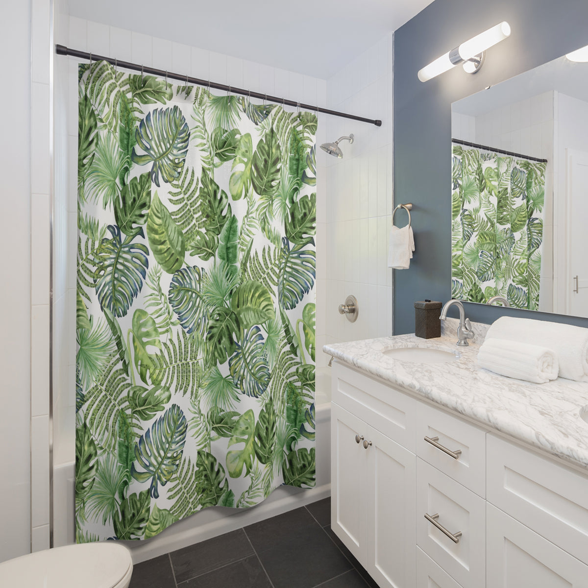 A modern bathroom with a white vanity, a shower curtain with a tropical leaf pattern, and a mirror above the sink.