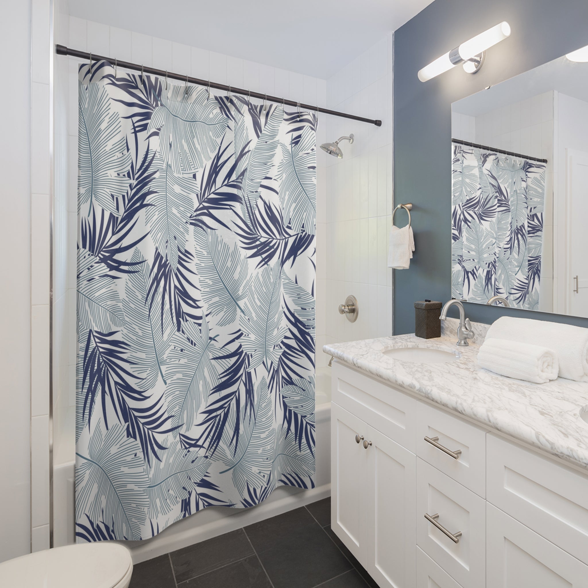 a modern bathroom with a white vanity, a large blue and white shower curtain with a tropical leaf pattern, and a white countertop with a sink.