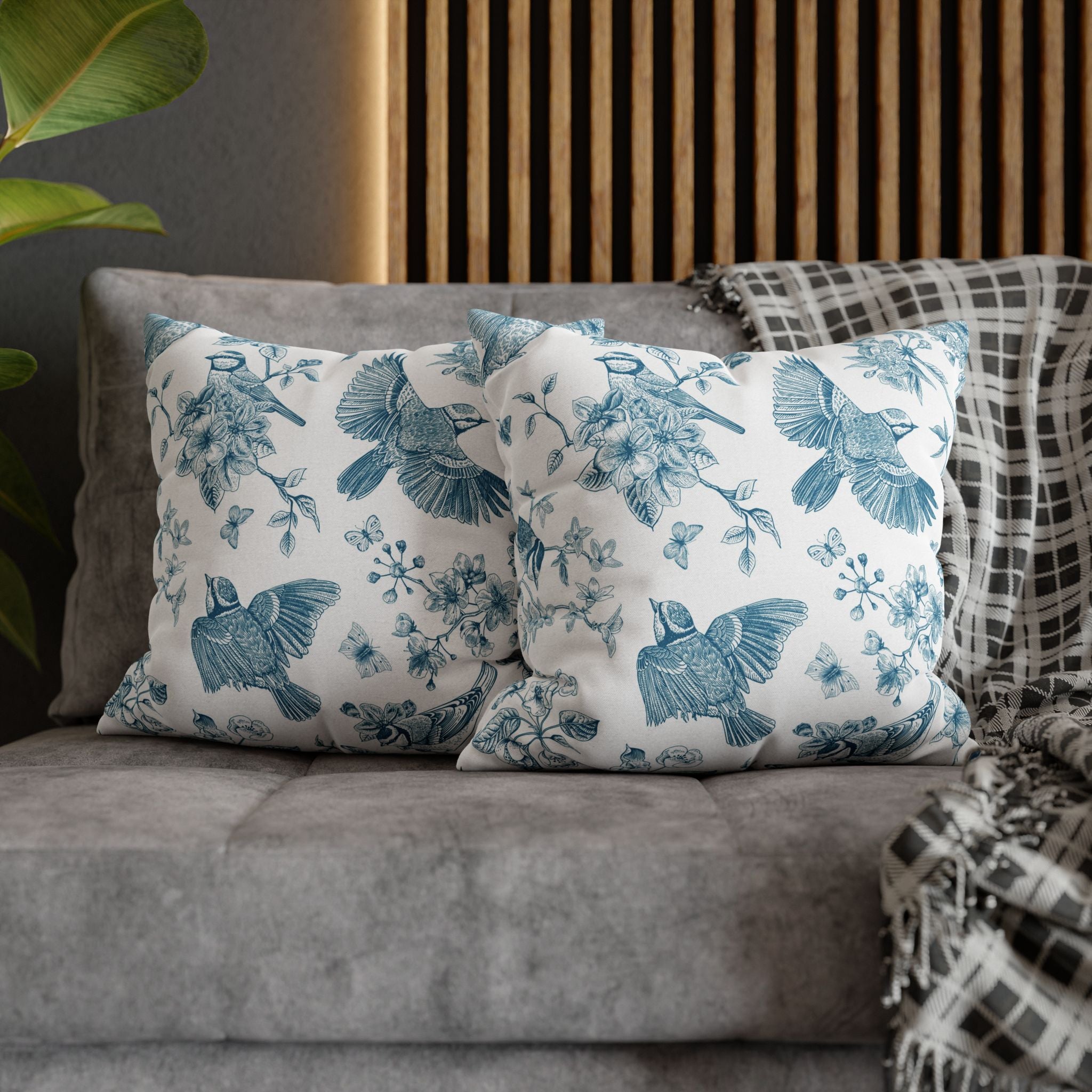 a gray couch with three decorative throw pillows on it. The pillows have a blue and white floral pattern and are arranged in a row on the couch.