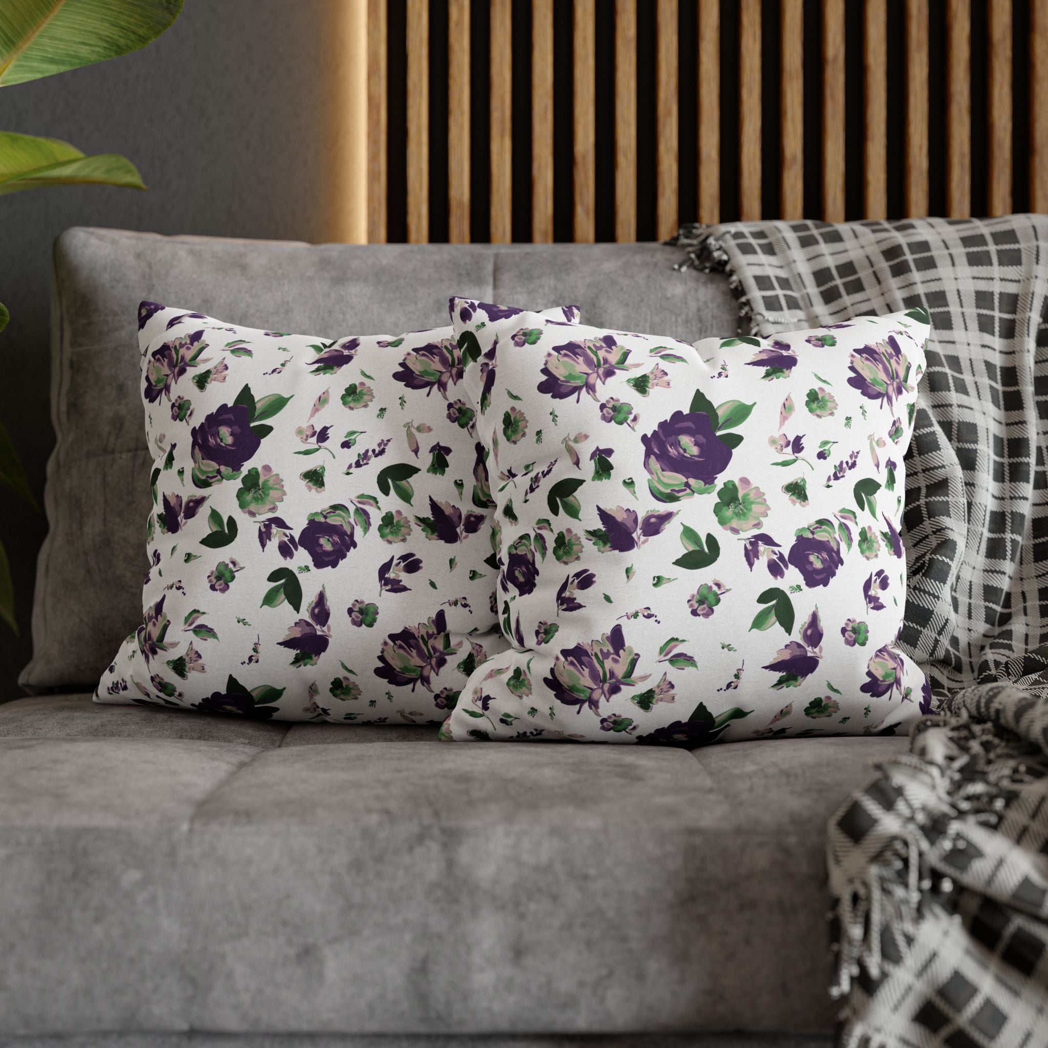 a gray couch with two throw pillows featuring a floral pattern in shades of purple and green. The pillows are arranged on the couch, creating a cozy and inviting atmosphere.