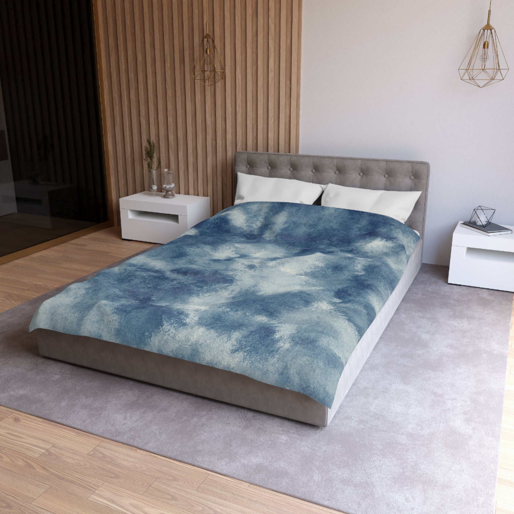 a modern bedroom with a gray tufted headboard, a blue and white patterned comforter, and a white nightstand next to the bed.