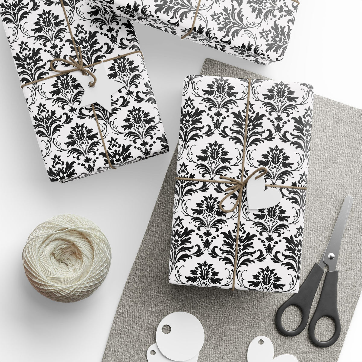 Classic black and white damask wrapping paper on gifts tied with twine, with gift tags and scissors