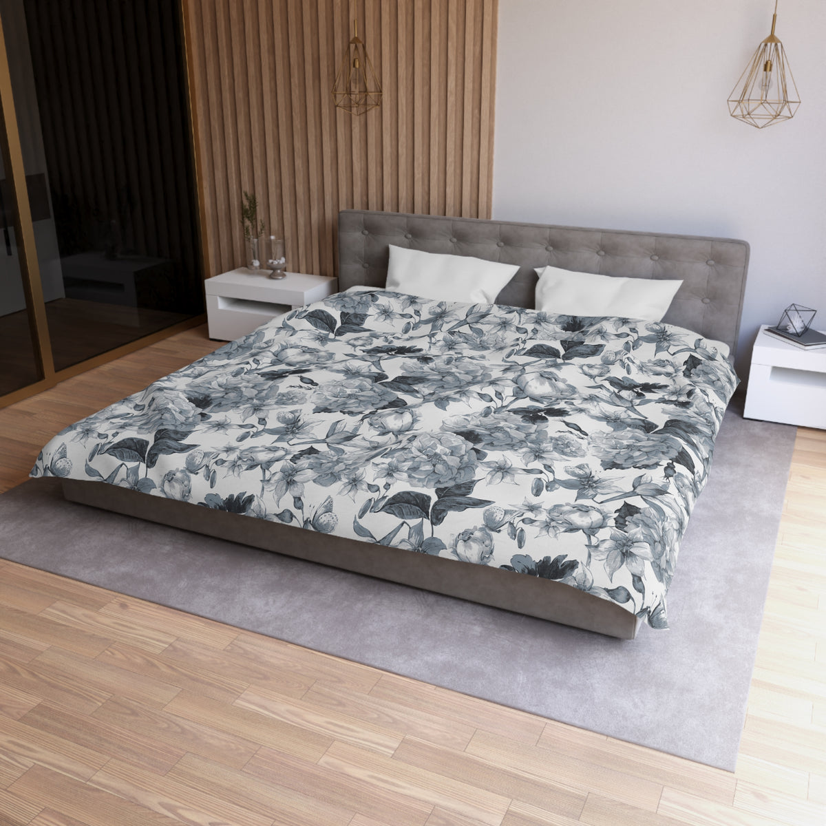 a modern bedroom with a large bed, a gray headboard, and a floral patterned comforter. The room has a wooden floor and white walls, creating a serene and elegant atmosphere.