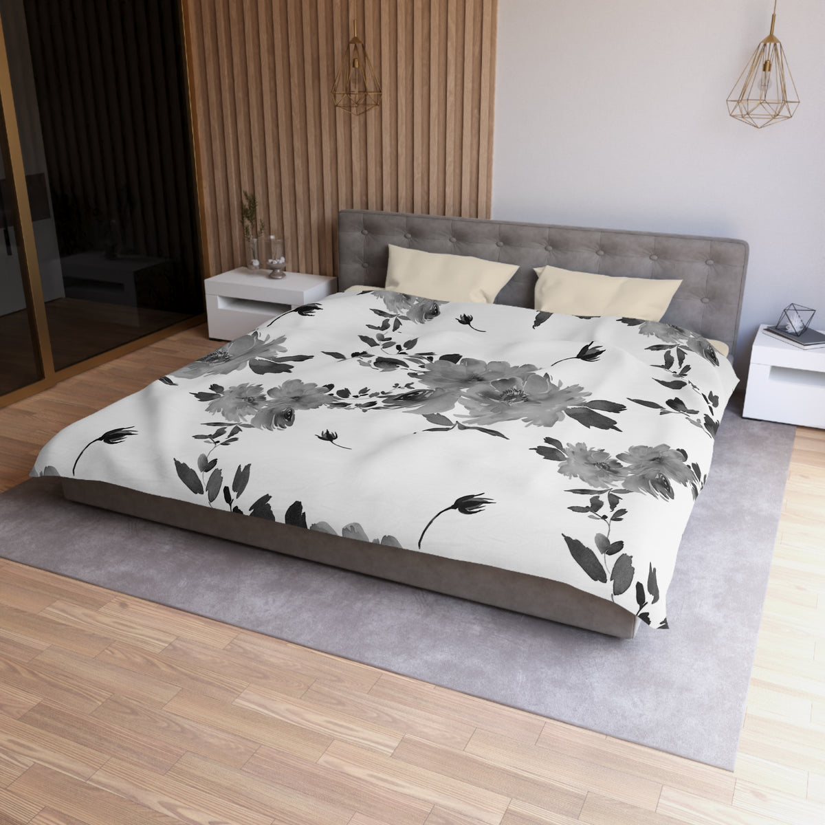a modern bedroom with a large bed, a gray headboard, and a white floral comforter. The room has a wooden floor and a white nightstand on each side of the bed. There is also a pendant light hanging above the bed.