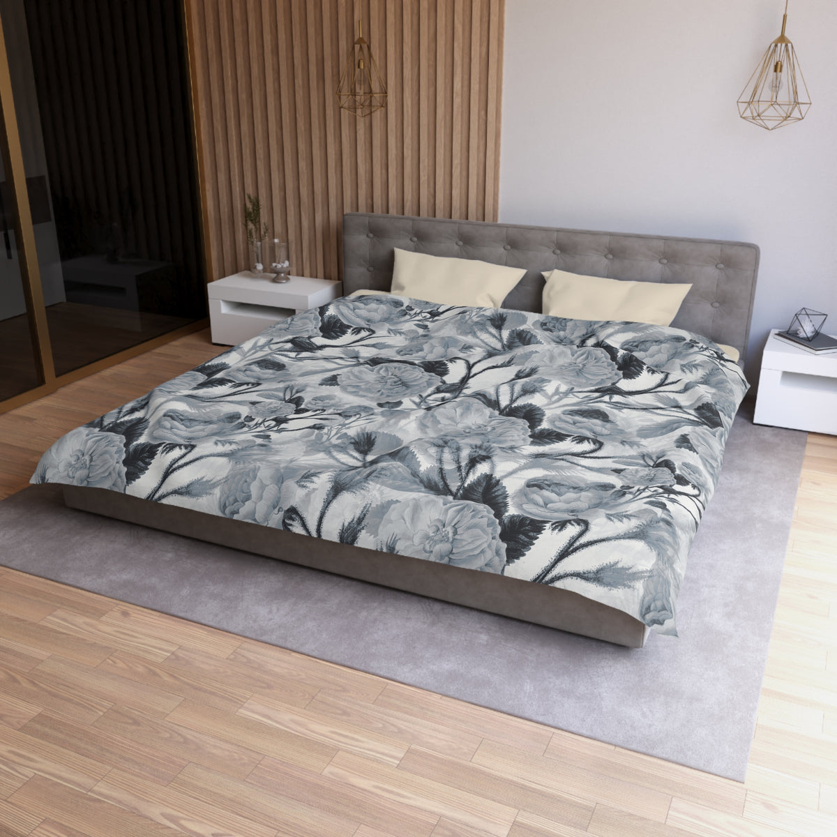 a modern bedroom with a large bed, a gray headboard, and a gray and white floral comforter. The room has a wooden floor and white walls, creating a serene and elegant atmosphere.