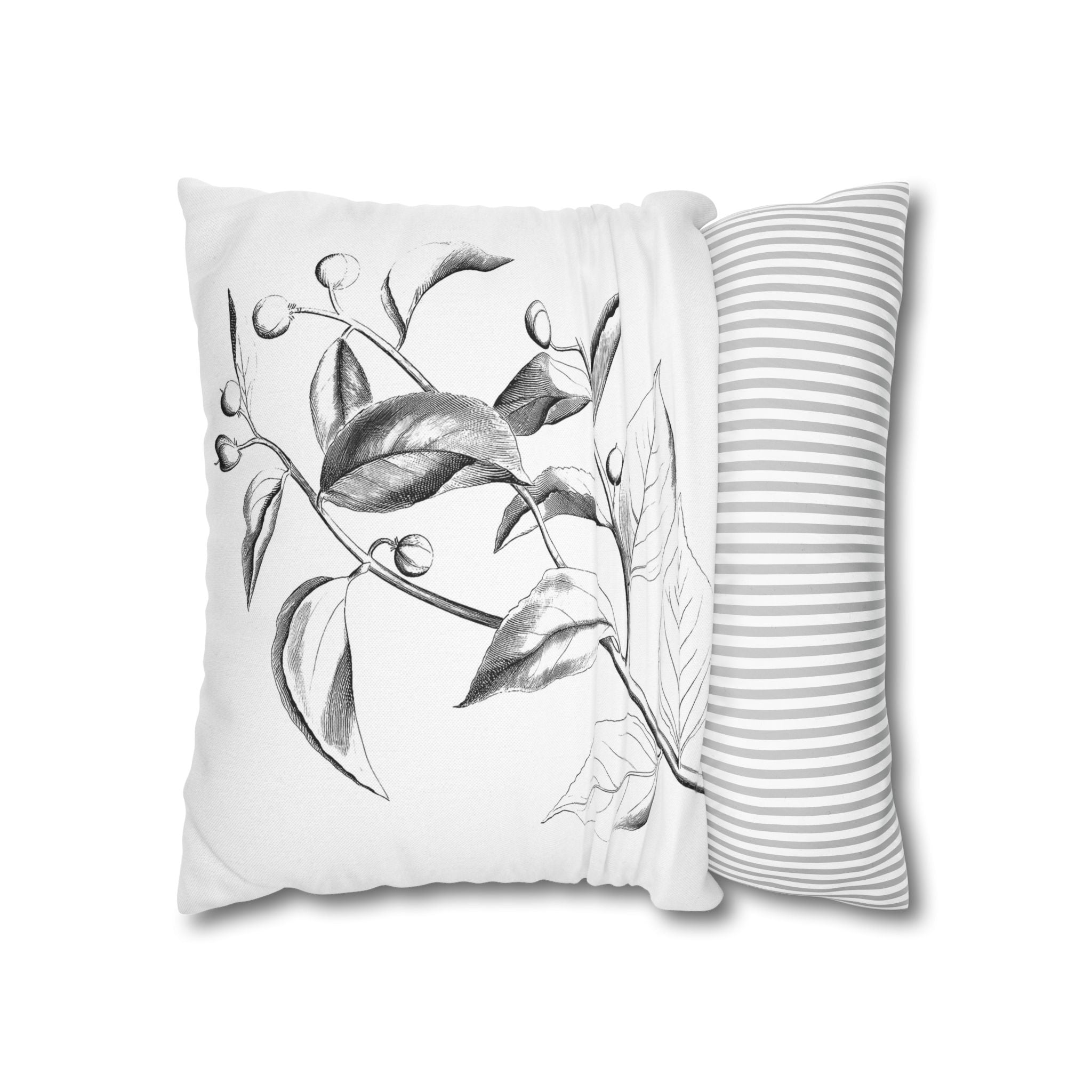 a white pillow with a black and white illustration of leaves and flowers on it, along with a gray and white striped pillow on the right side.