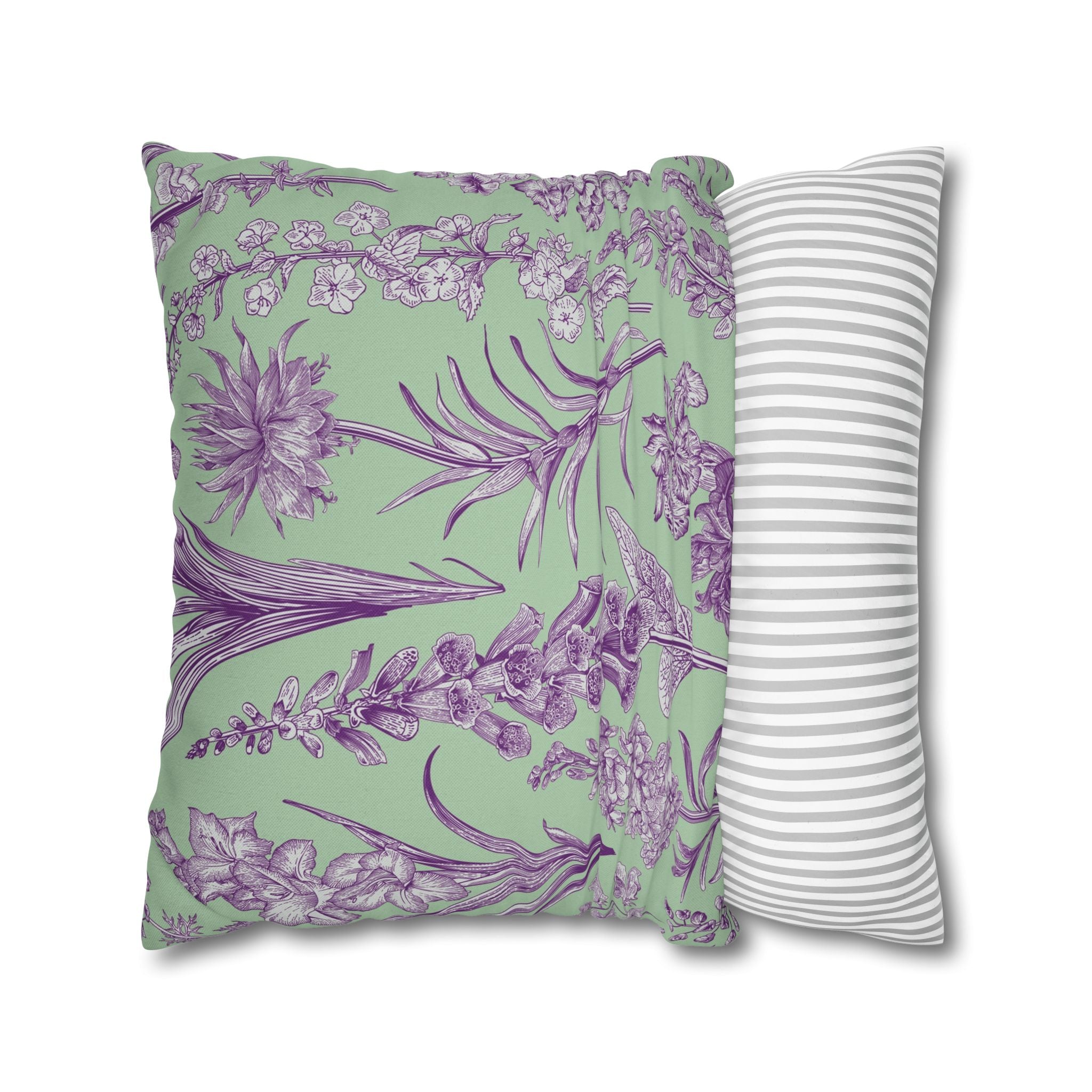 a square throw pillow with a vibrant green background and a pattern of purple flowers and leaves. The pillow is placed next to a matching white and gray striped pillow, creating a visually appealing and coordinated display.
