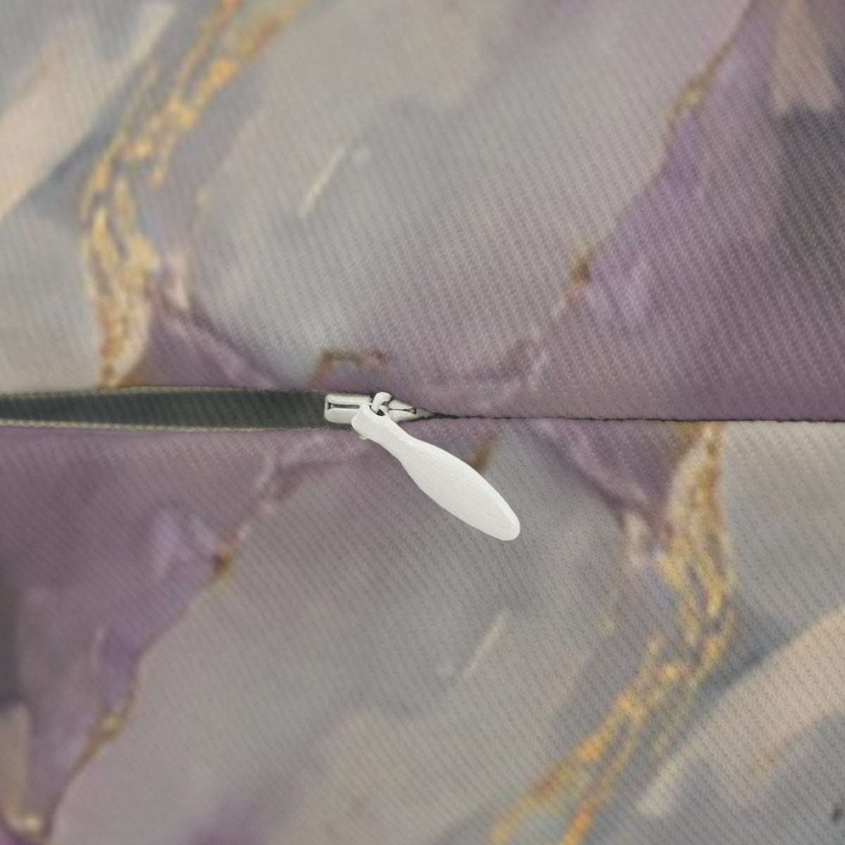 A close-up view of a zipper on a fabric, with a white plastic zipper pull visible.