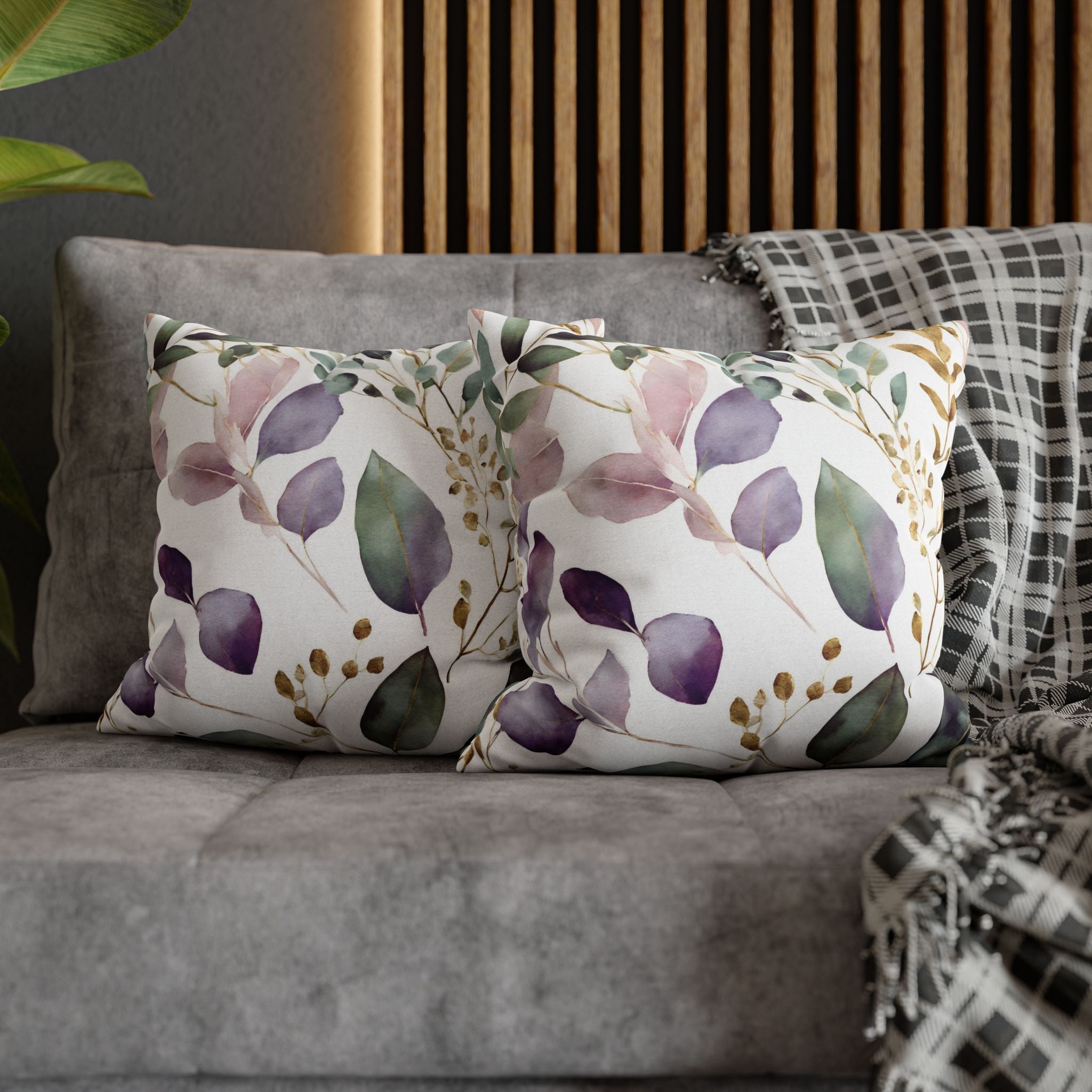 a gray couch with two decorative throw pillows featuring a floral pattern in shades of purple and green. The pillows are placed on the couch, creating a cozy and inviting atmosphere.