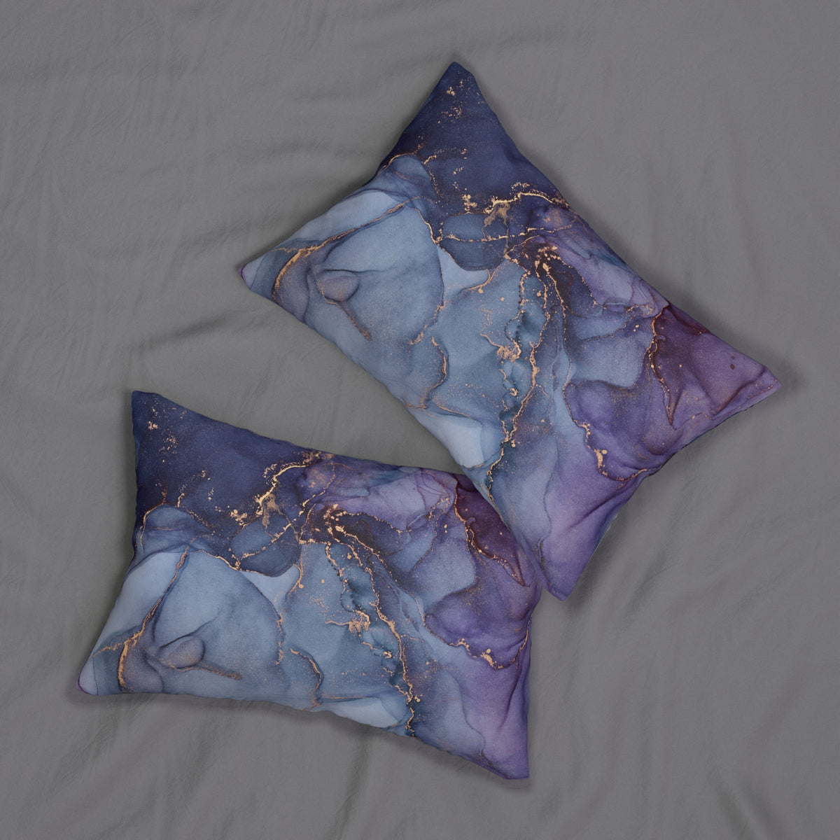 two decorative pillows with a marble-like pattern in shades of blue and purple, featuring gold accents.