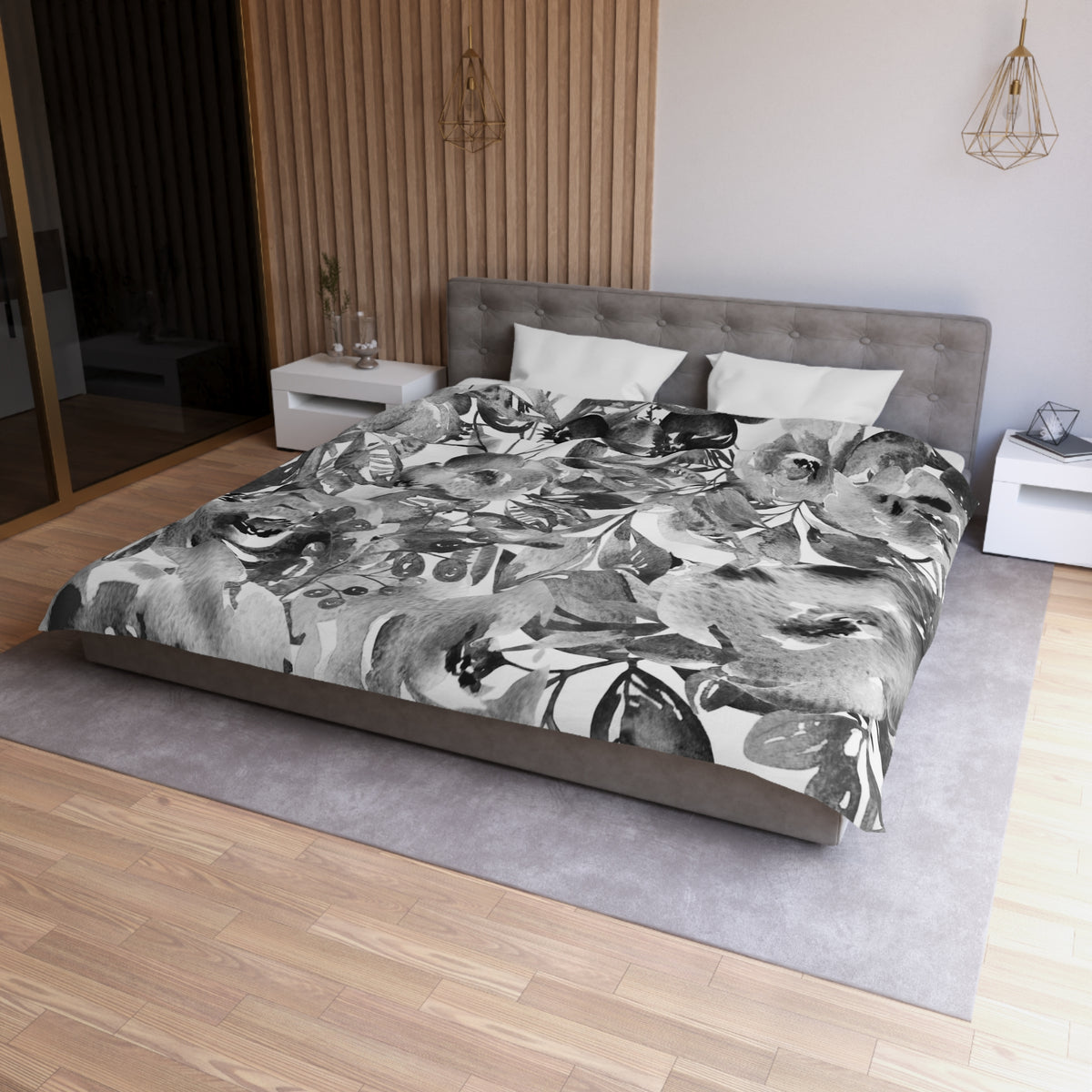 a modern bedroom with a large bed covered in a black and white floral patterned comforter. The bed is positioned against a wall with a wooden paneling. The room also features a nightstand, a pendant light, and a rug on the floor.
