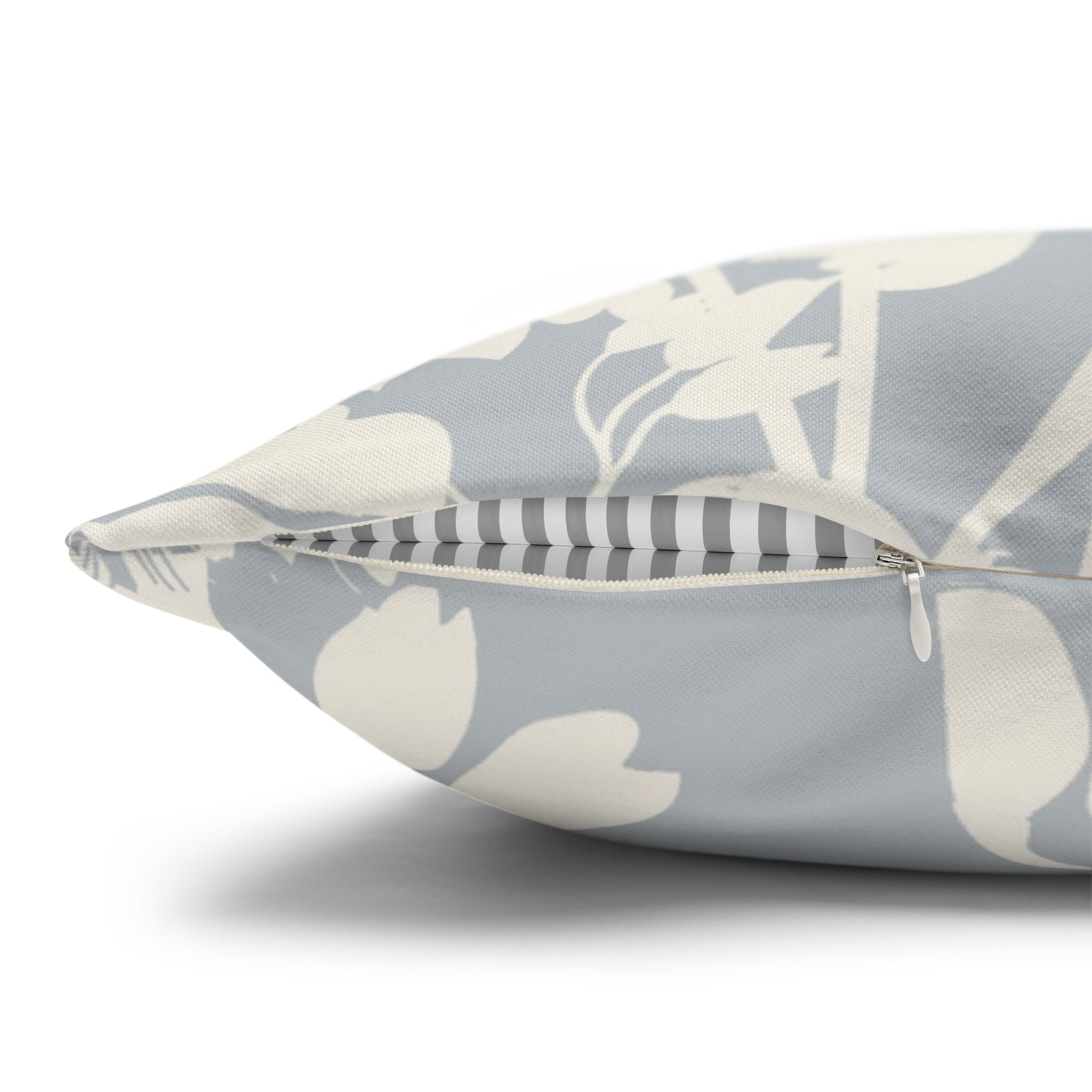 a close-up view of a gray and white floral patterned pillow with a zipper visible.