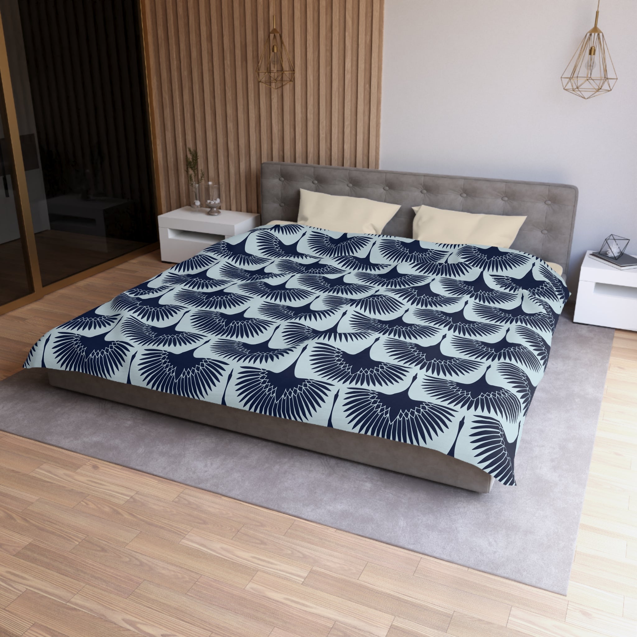 a modern bedroom with a large bed featuring a blue and white patterned comforter. The bed is positioned against a wall with a wooden panel. The room also includes a nightstand and a pendant light fixture.