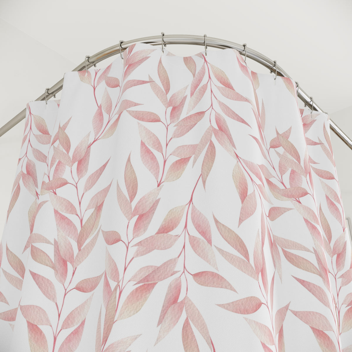a shower curtain with a pink leaf pattern hanging from a curved metal rod.