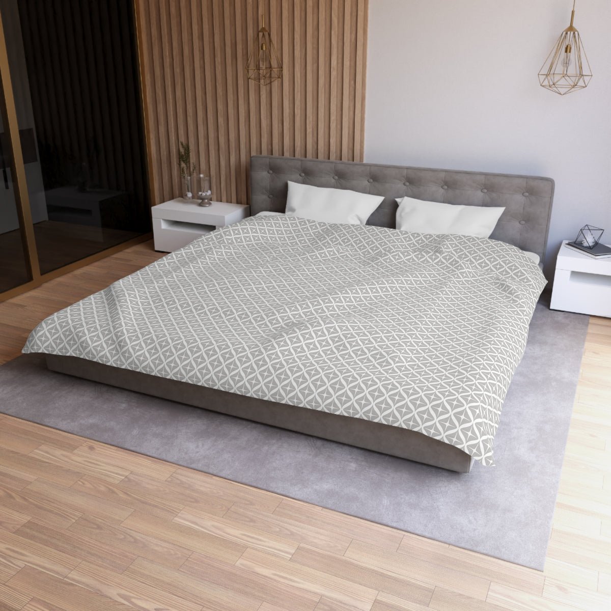 a modern bedroom with a large bed, a gray headboard, and a gray and white patterned comforter. The room has a wooden floor and white walls, creating a clean and minimalist aesthetic.
