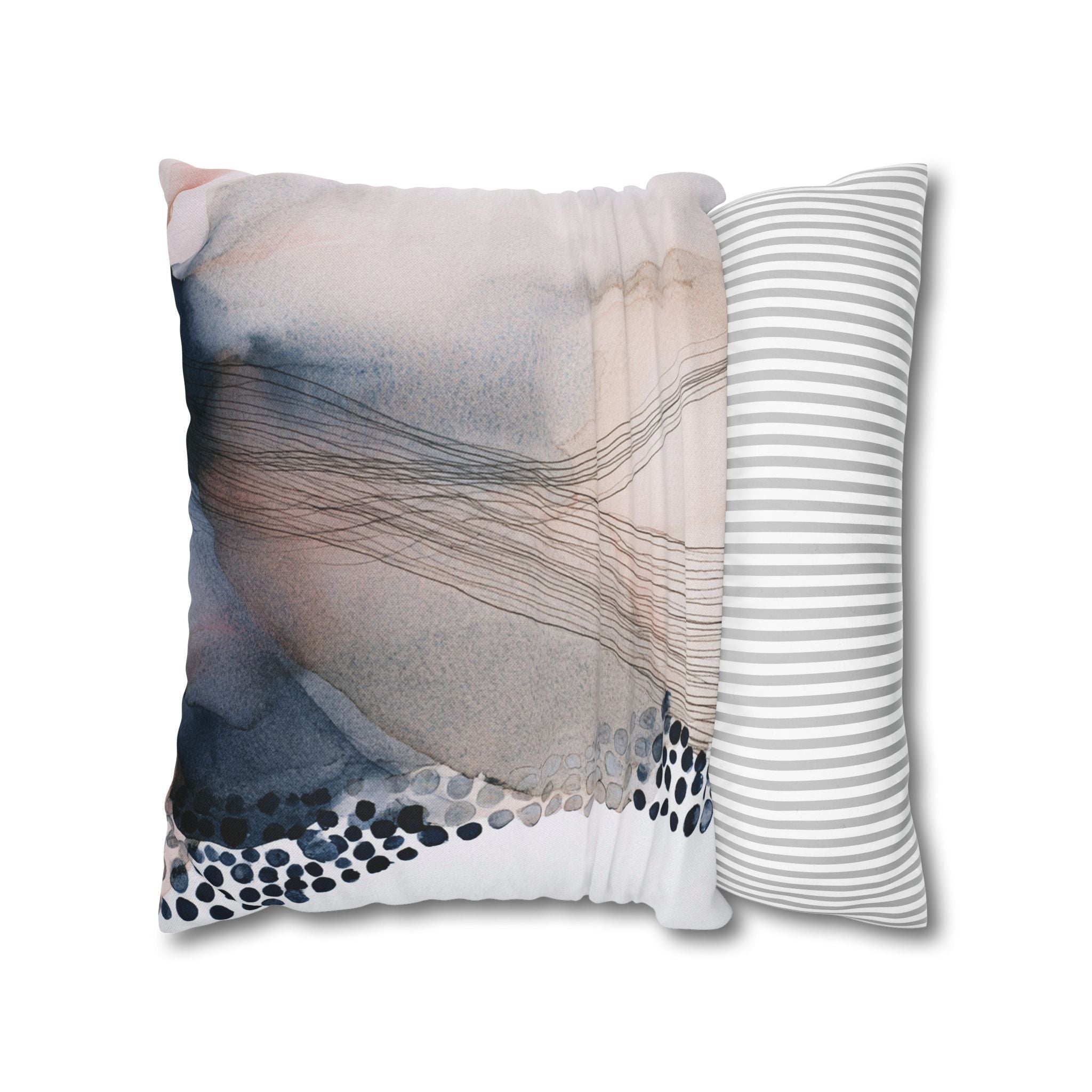 a square pillow with a watercolor-like abstract pattern in shades of pink, blue, and gray, along with a striped pillow on the right side.