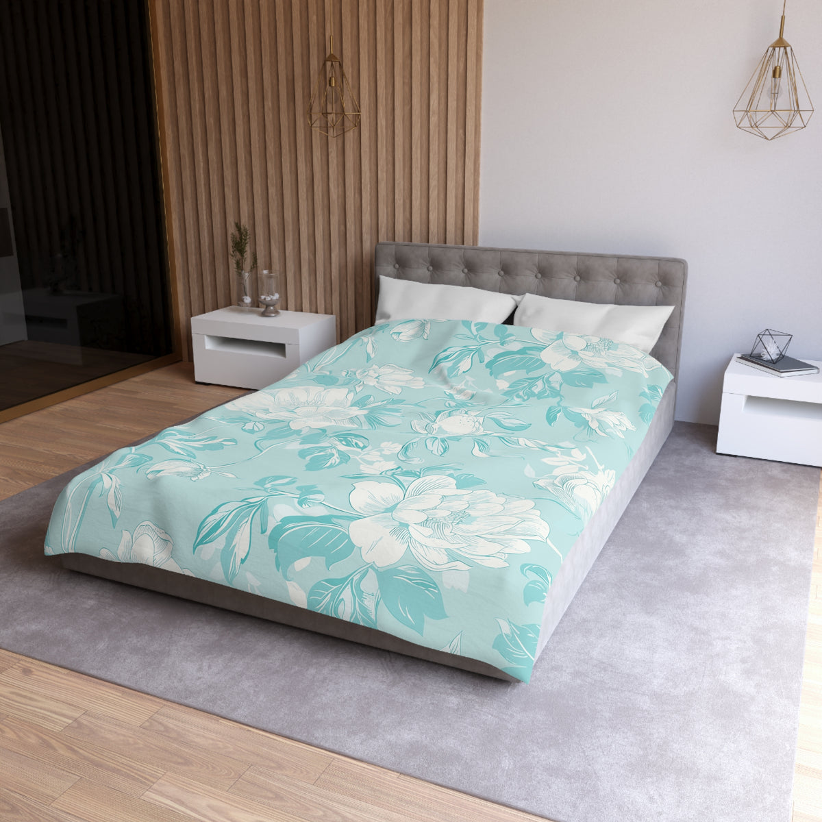 a modern bedroom with a large bed, a gray headboard, and a floral patterned comforter. The room has a neutral color scheme with white walls and a gray carpet. There are two white nightstands on either side of the bed, and a pendant light hangs above the bed.