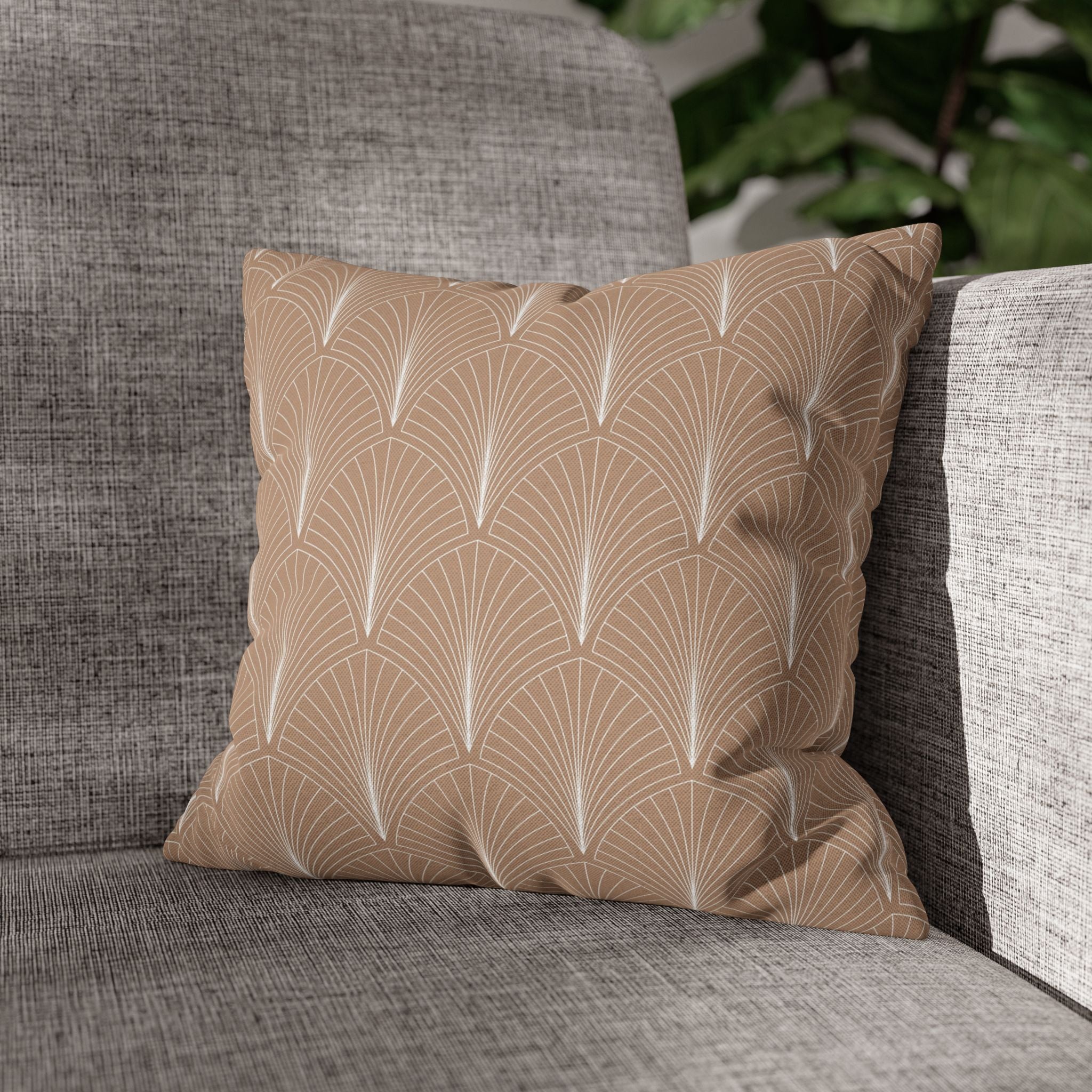 A beige throw pillow with a repeating pattern of white lines sits on a gray couch.