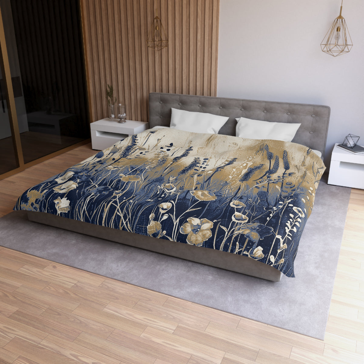 a bedroom with a large bed covered in a blue and gold floral comforter. The bed is positioned against a wall with a wooden panel. The room has a wooden floor and a white nightstand on the left side of the bed. There is also a pendant light hanging above the bed.