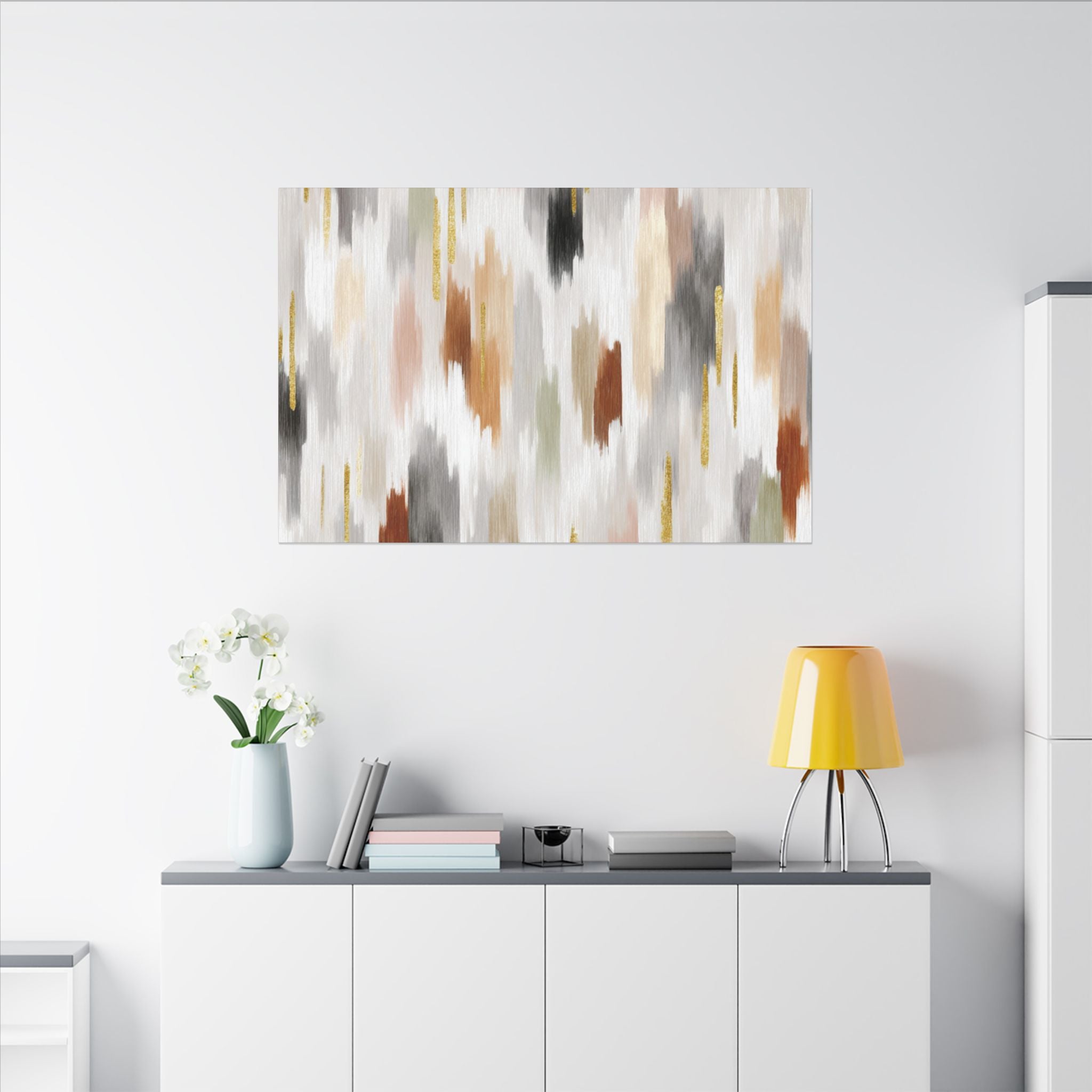 a modern living room with a white wall, a white cabinet, a yellow lamp, a vase with white flowers, and a framed abstract painting hanging above the cabinet.