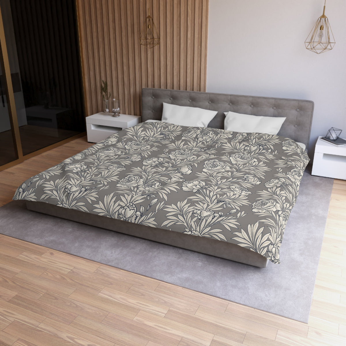 a modern bedroom with a large bed, a gray headboard, and a gray and white floral patterned comforter. The room has a wooden floor and white walls, creating a serene and elegant atmosphere.