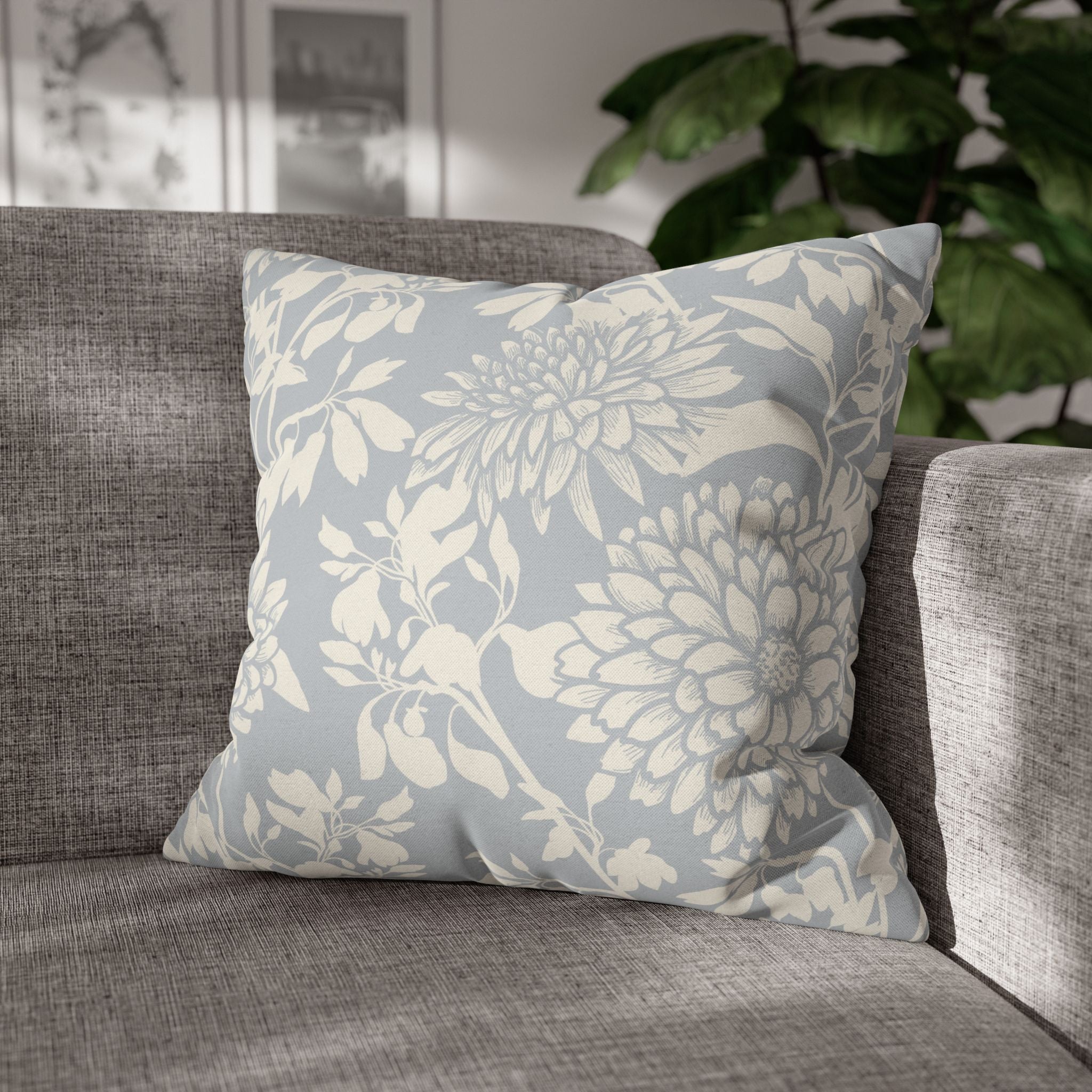 A gray sofa with a decorative pillow featuring a floral pattern in shades of blue and white.