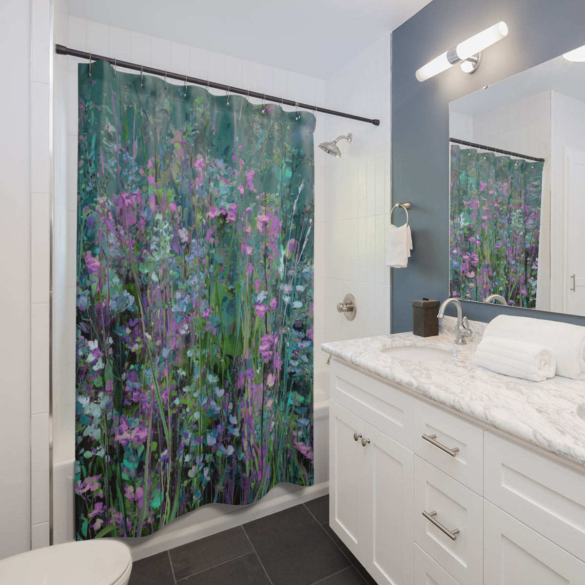 A bathroom with a shower curtain featuring a vibrant floral pattern in shades of green, purple, and pink. The bathroom has a white vanity and marble countertop, and a large mirror above the sink.