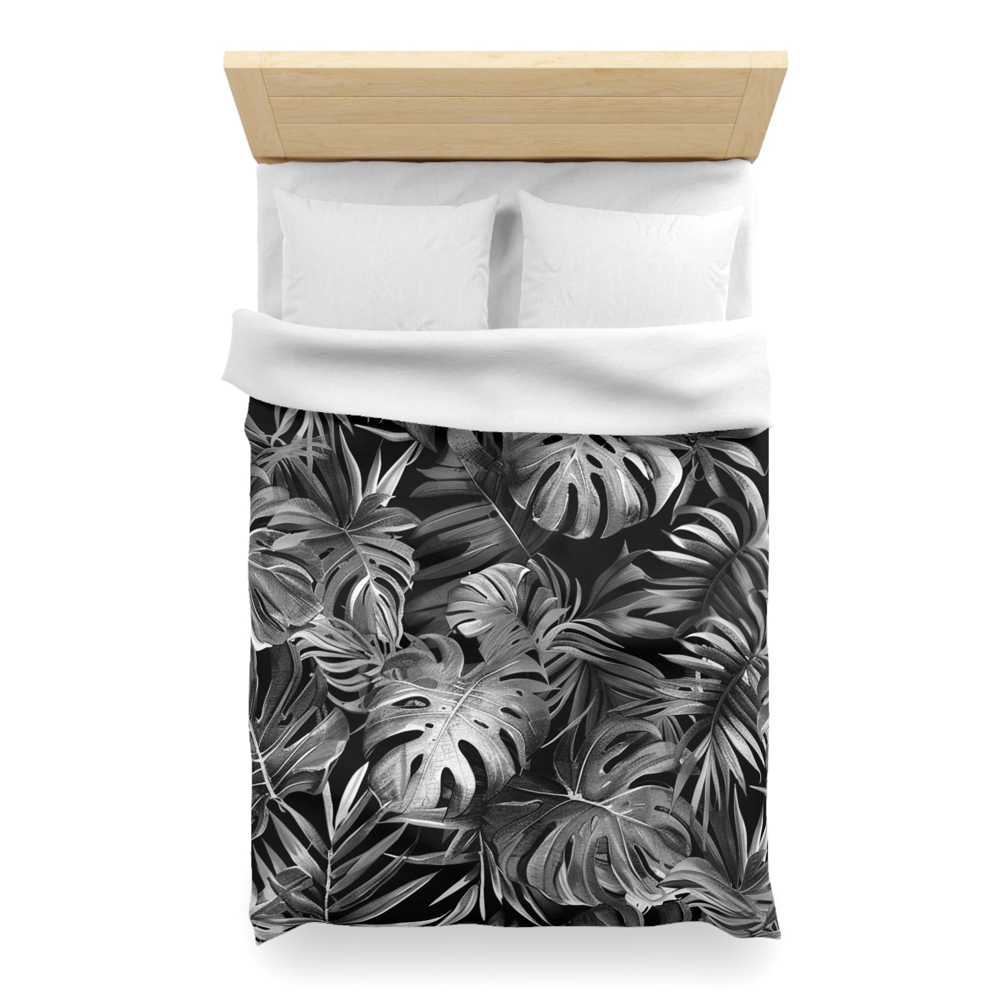 a bed with a black and white tropical leaf pattern on the comforter and pillowcases.