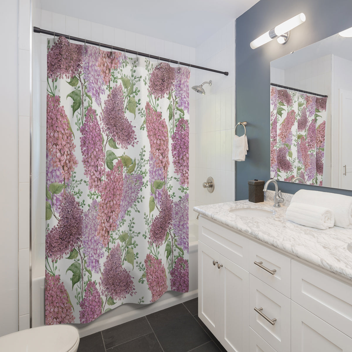 A bathroom with a white vanity, a shower curtain with a floral pattern in shades of pink and purple, and a mirror above the vanity.