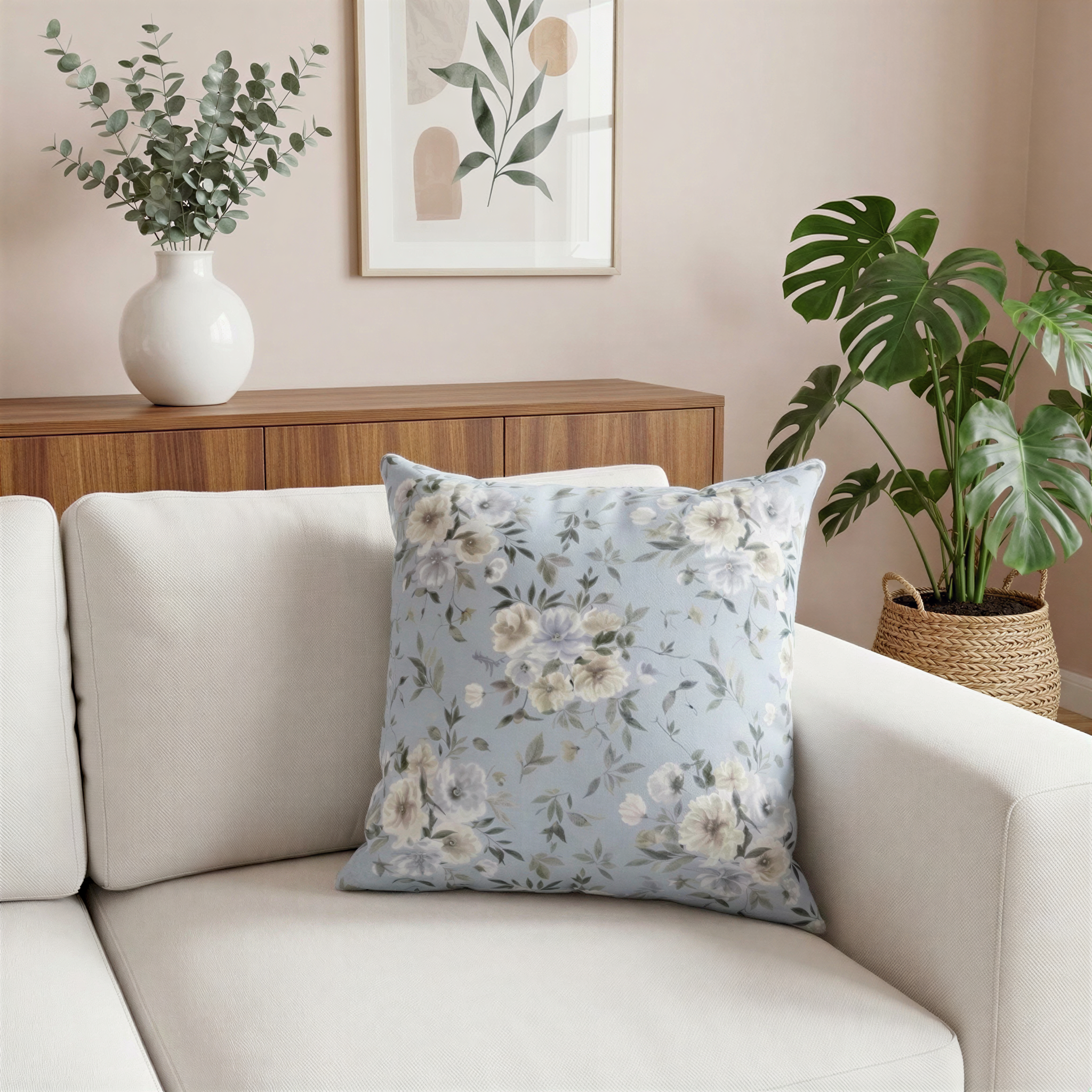 a living room with a white sofa, a floral throw pillow, and a wooden cabinet. The room has a light pink color scheme, and there are two potted plants, one on the left side and one on the right side of the sofa. The overall scene has a cozy and inviting atmosphere.